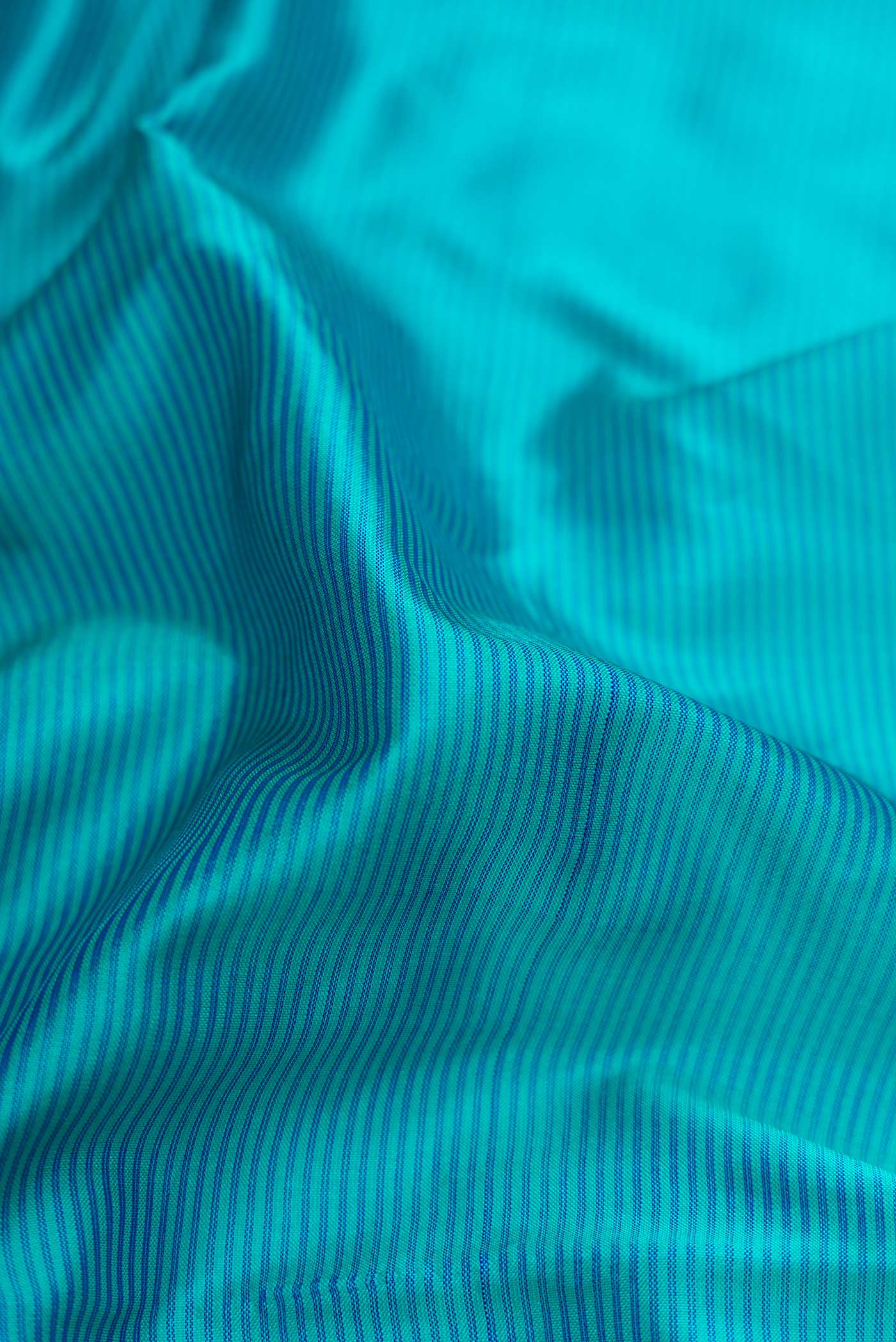 Close up of Peacock Blue Dual Tone Maheshwari Silk Saree with Stripes on the body and Zari Border.  displaying folds