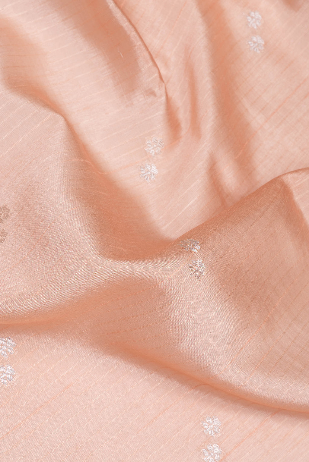 Close up of Peach Tussar Silk Saree with Zari Butta on the body and Fancy Border.  displaying folds