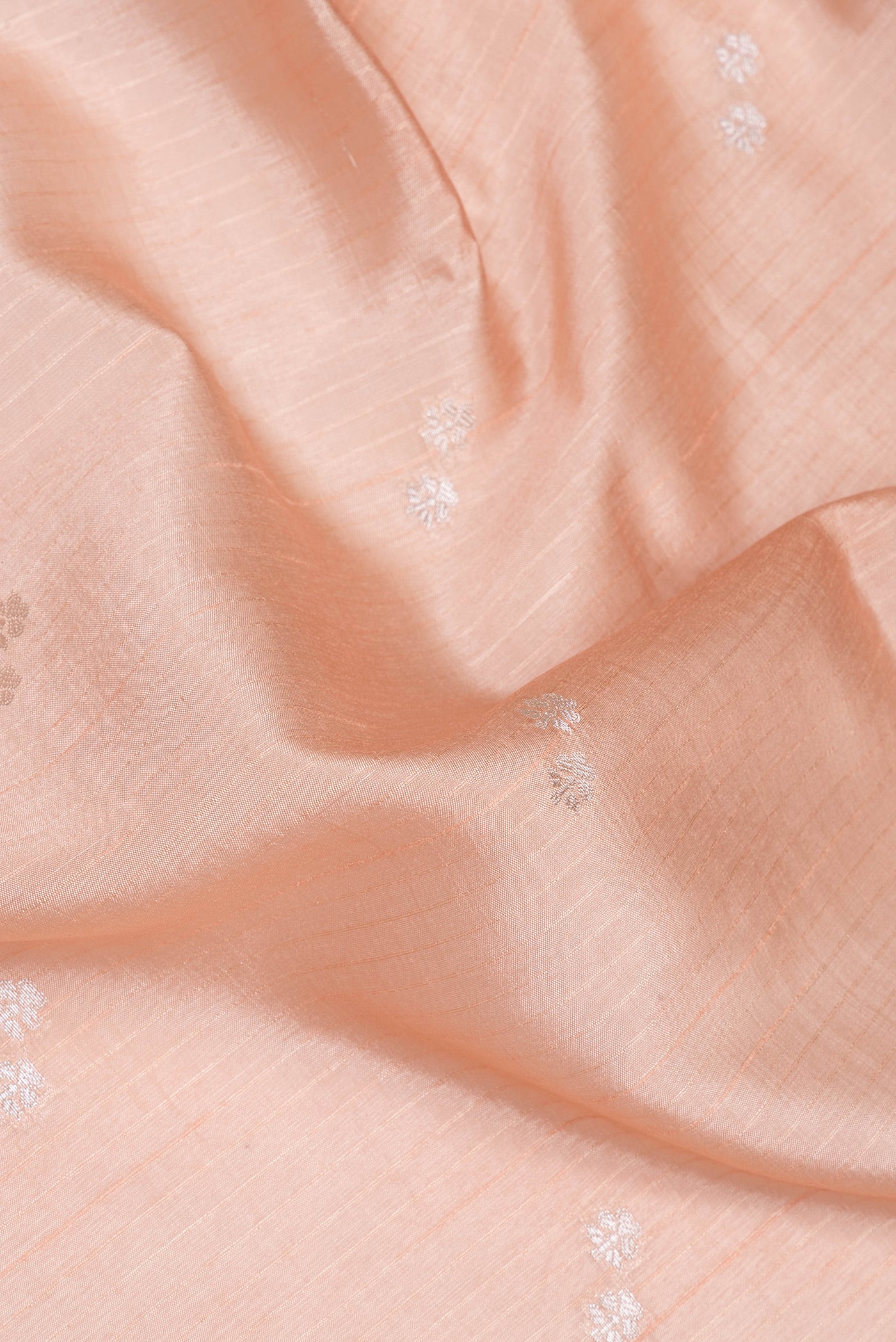 Close up of Peach Tussar Silk Saree with Zari Butta on the body and Fancy Border.  displaying folds