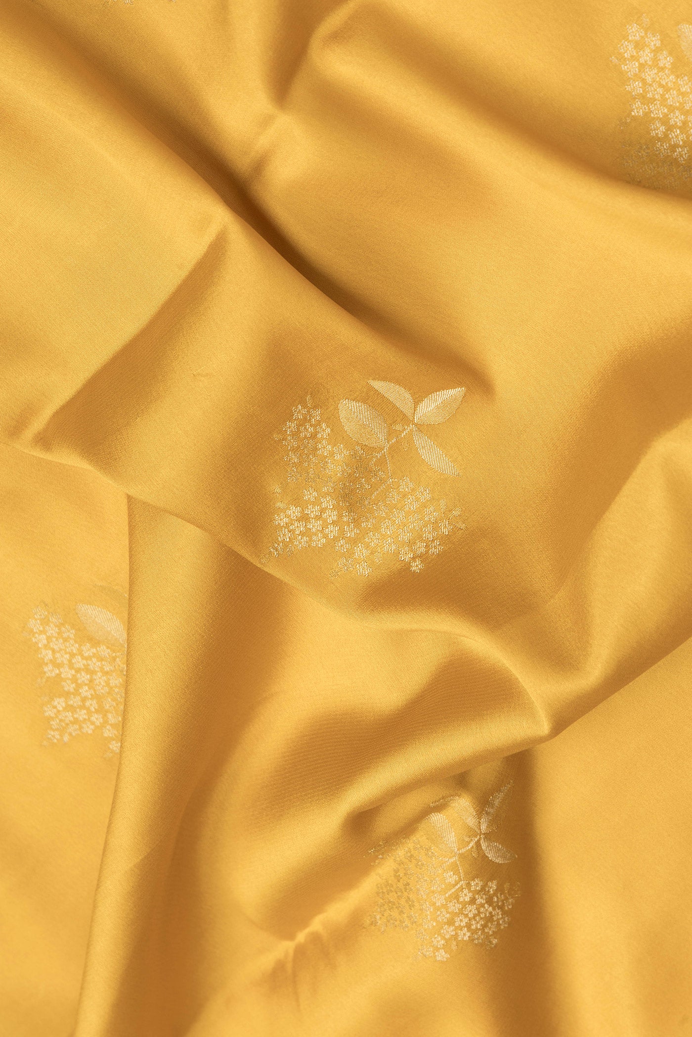 Close up of Mustard Dual Tone Mysore Crepe Saree with Zari Butta on the body and Zari Border.  displaying folds