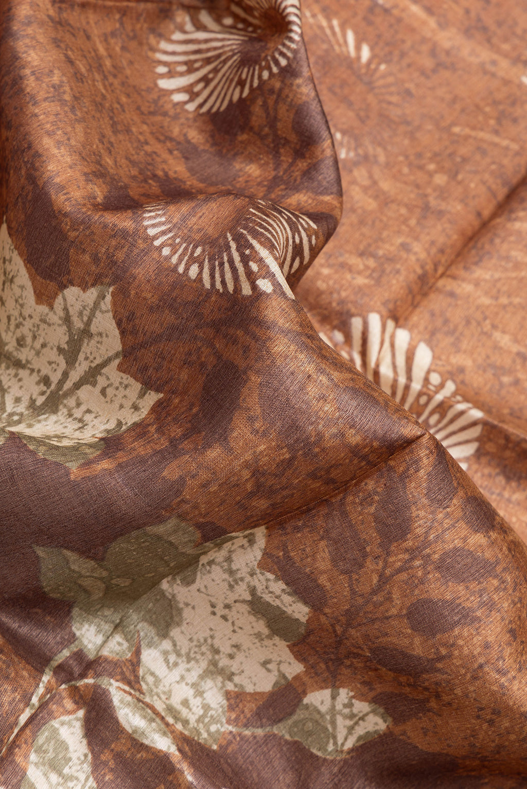 Close up of Brown Tussar Silk Saree with Printed design on the body and Zari Border.  displaying folds