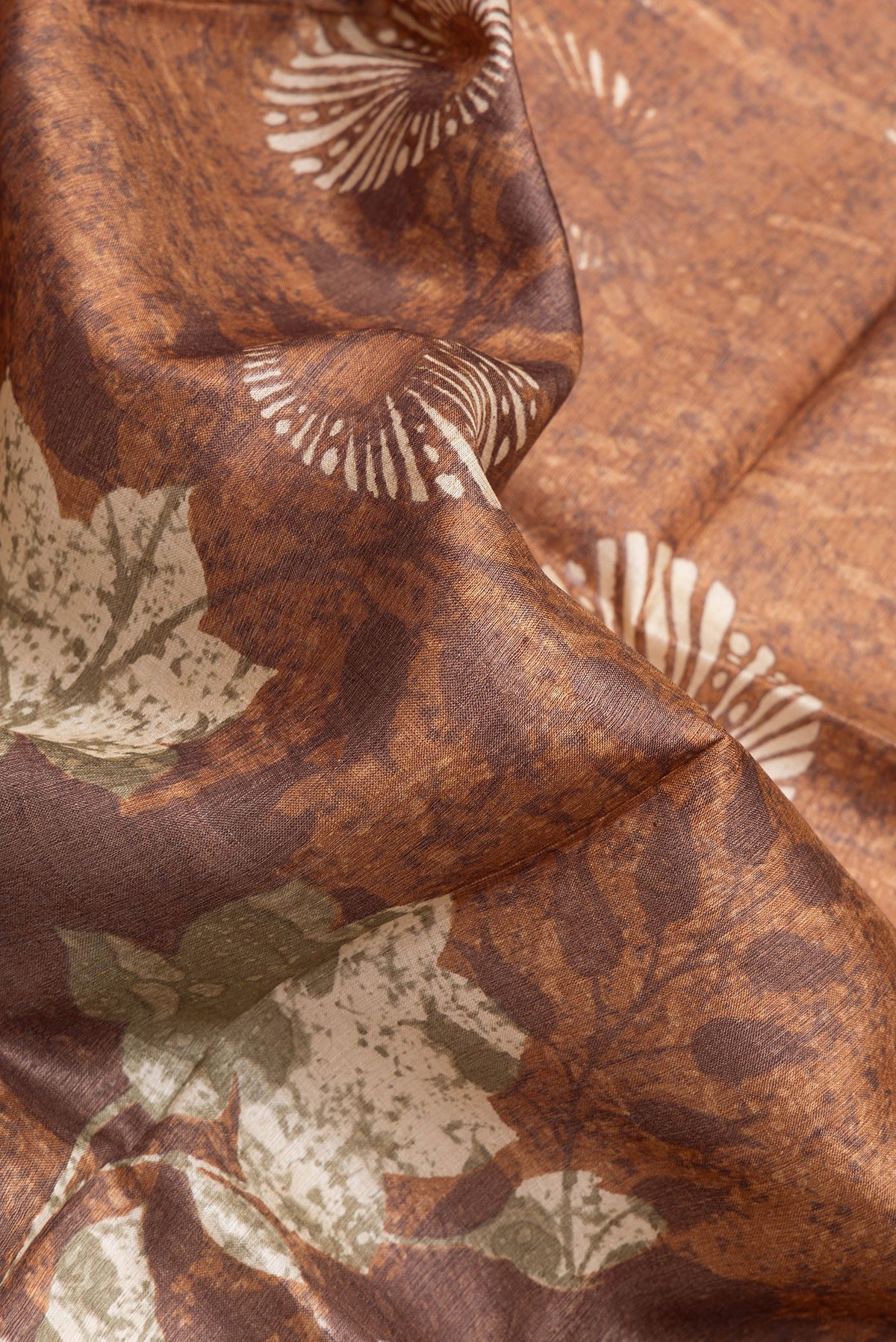 Close up of Brown Tussar Silk Saree with Printed design on the body and Zari Border.  displaying folds