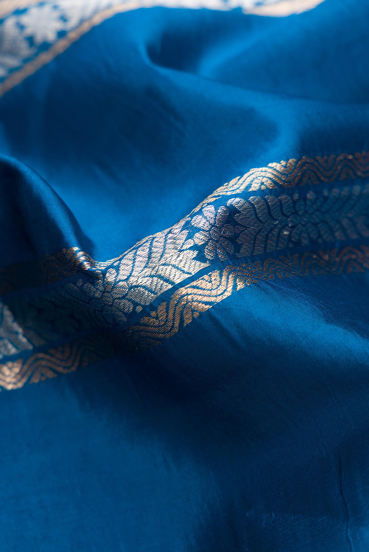 Close up of Peacock Blue Dual Tone Tussar Silk Saree with Stripes on the body and Zari Border.  displaying folds