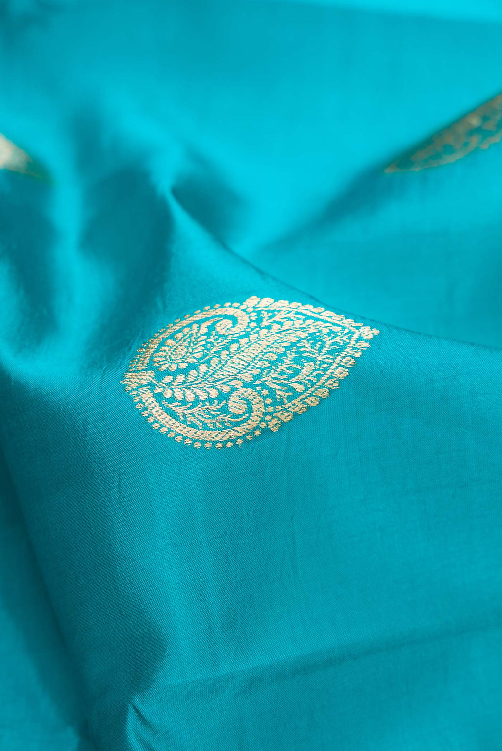 Close up of Peacock Blue Dual Tone Tussar Silk Saree with Zari Butta on the body and Fancy Border.  displaying folds