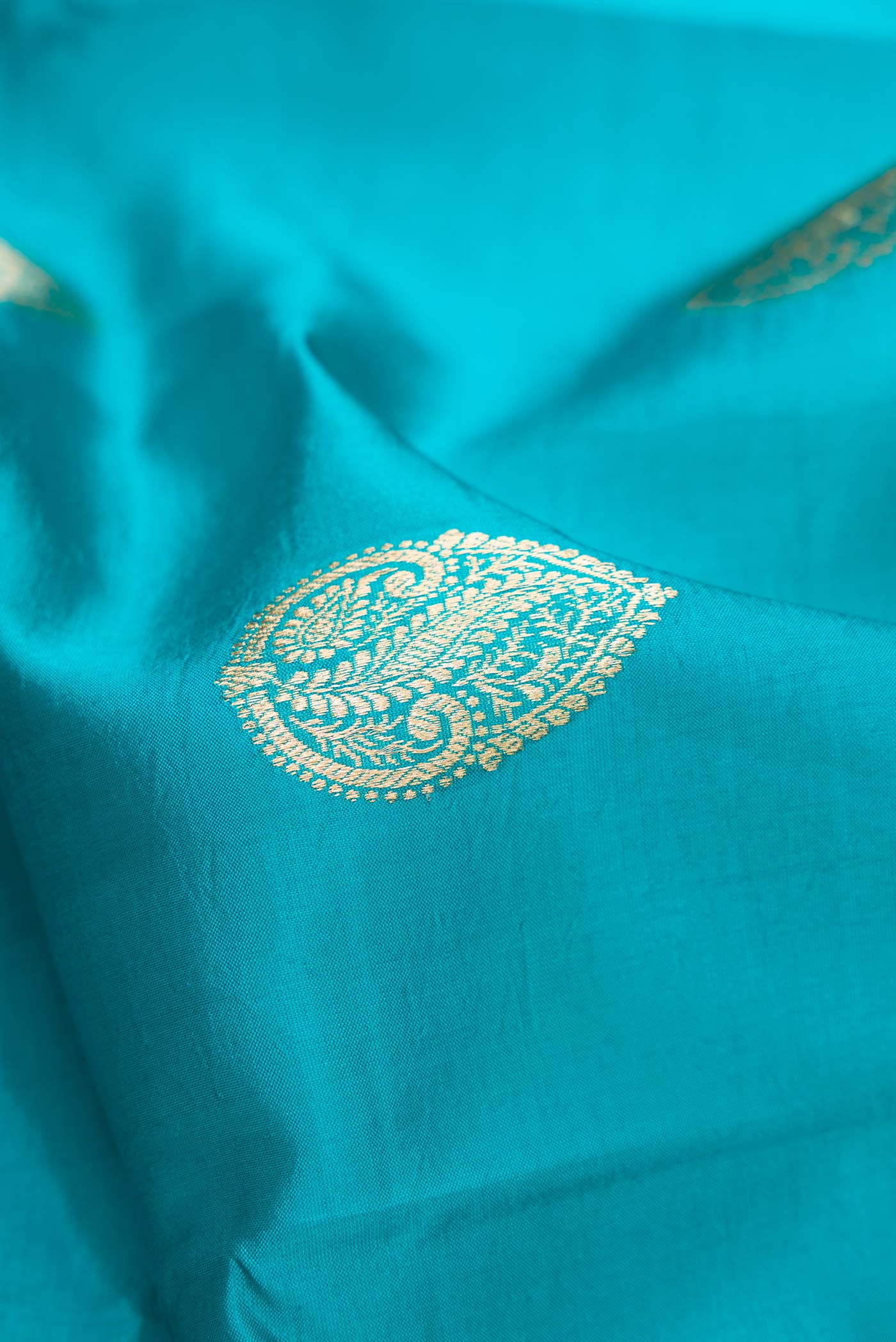 Close up of Peacock Blue Dual Tone Tussar Silk Saree with Zari Butta on the body and Fancy Border.  displaying folds