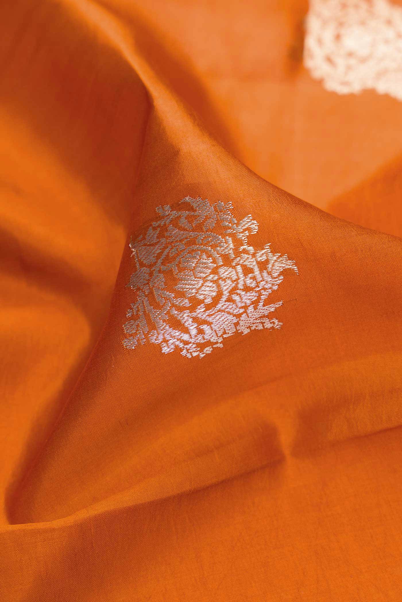 Close up of Orange Dual Tone Tussar Silk Saree with Zari Butta on the body and Fancy Border.  displaying folds