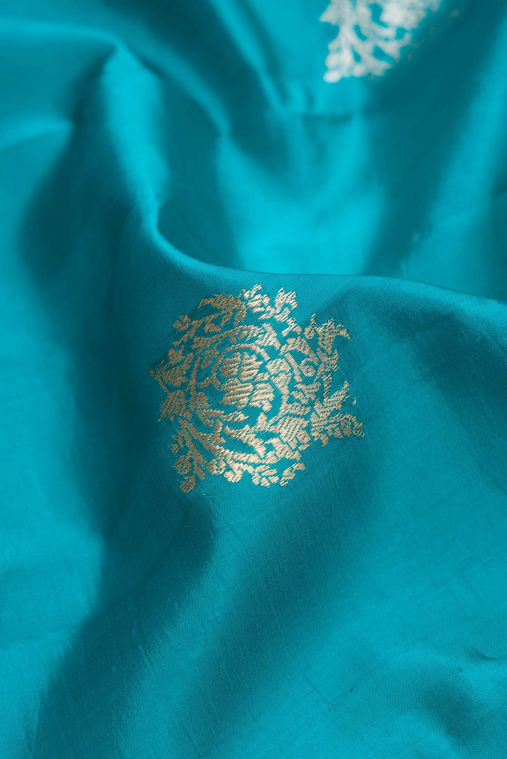 Close up of Peacock Blue Dual Tone Tussar Silk Saree with Zari Butta on the body and Zari Border.  displaying folds