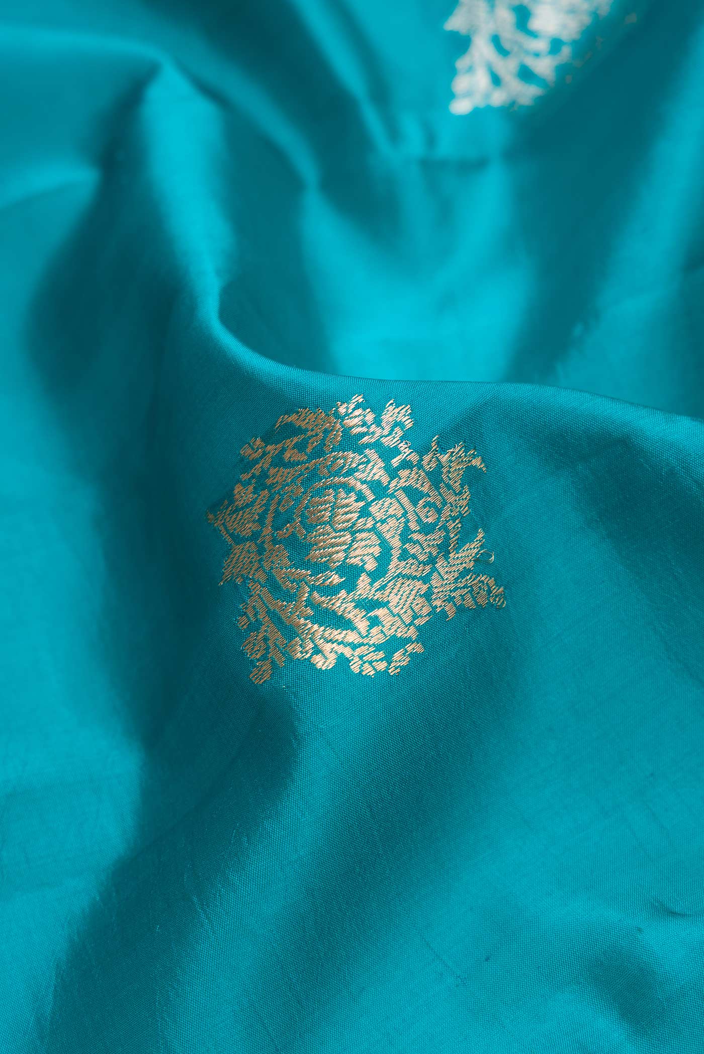 Close up of Peacock Blue Dual Tone Tussar Silk Saree with Zari Butta on the body and Zari Border.  displaying folds