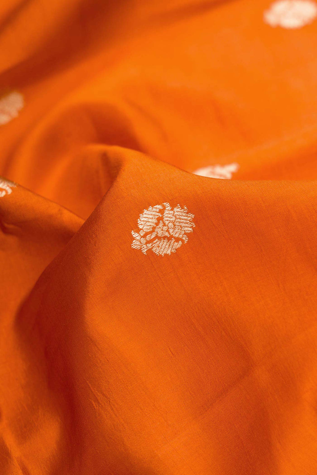 Close up of Orange Dual Tone Tussar Silk Saree with Zari Butta on the body and Zari Border.  displaying folds