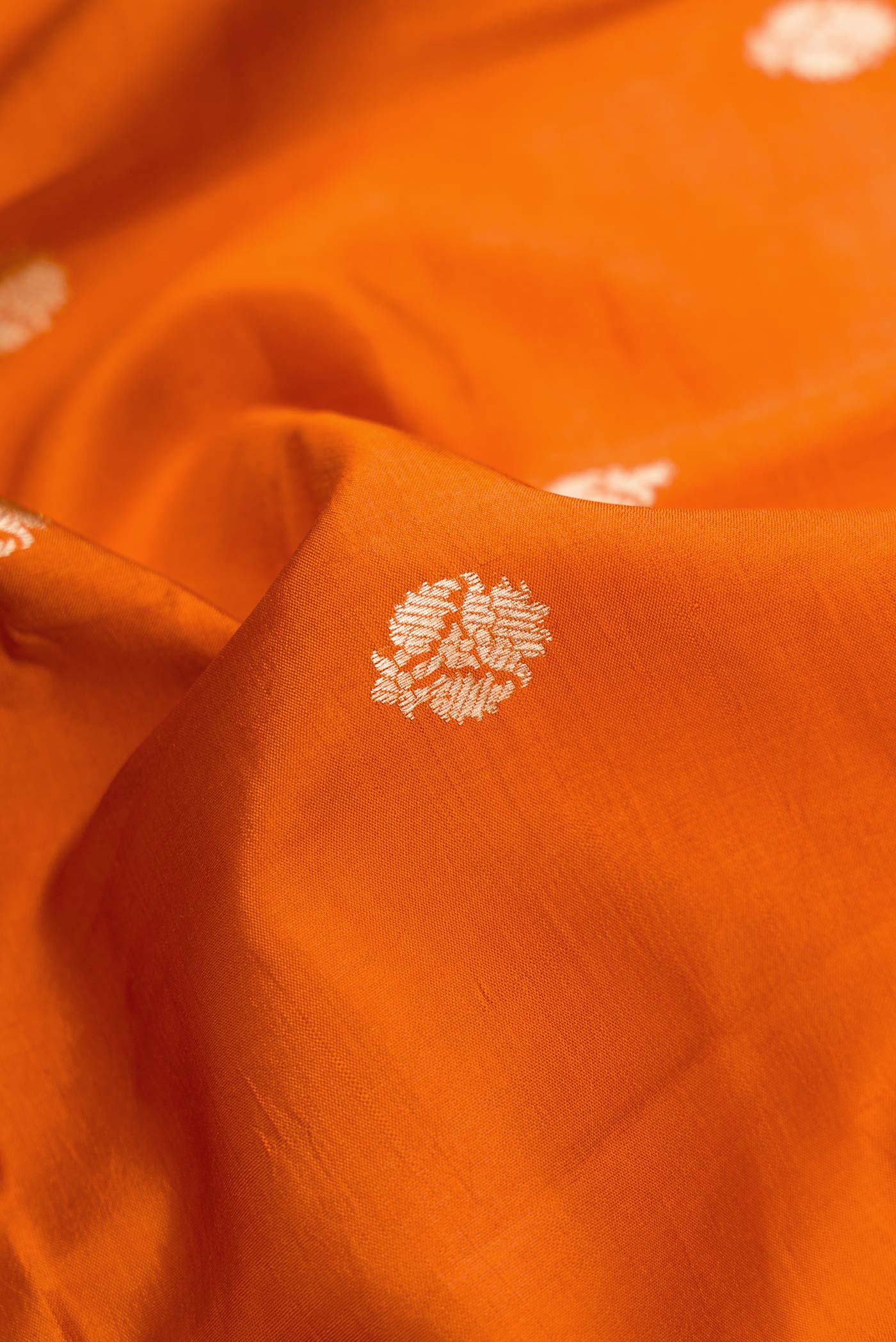 Close up of Orange Dual Tone Tussar Silk Saree with Zari Butta on the body and Zari Border.  displaying folds