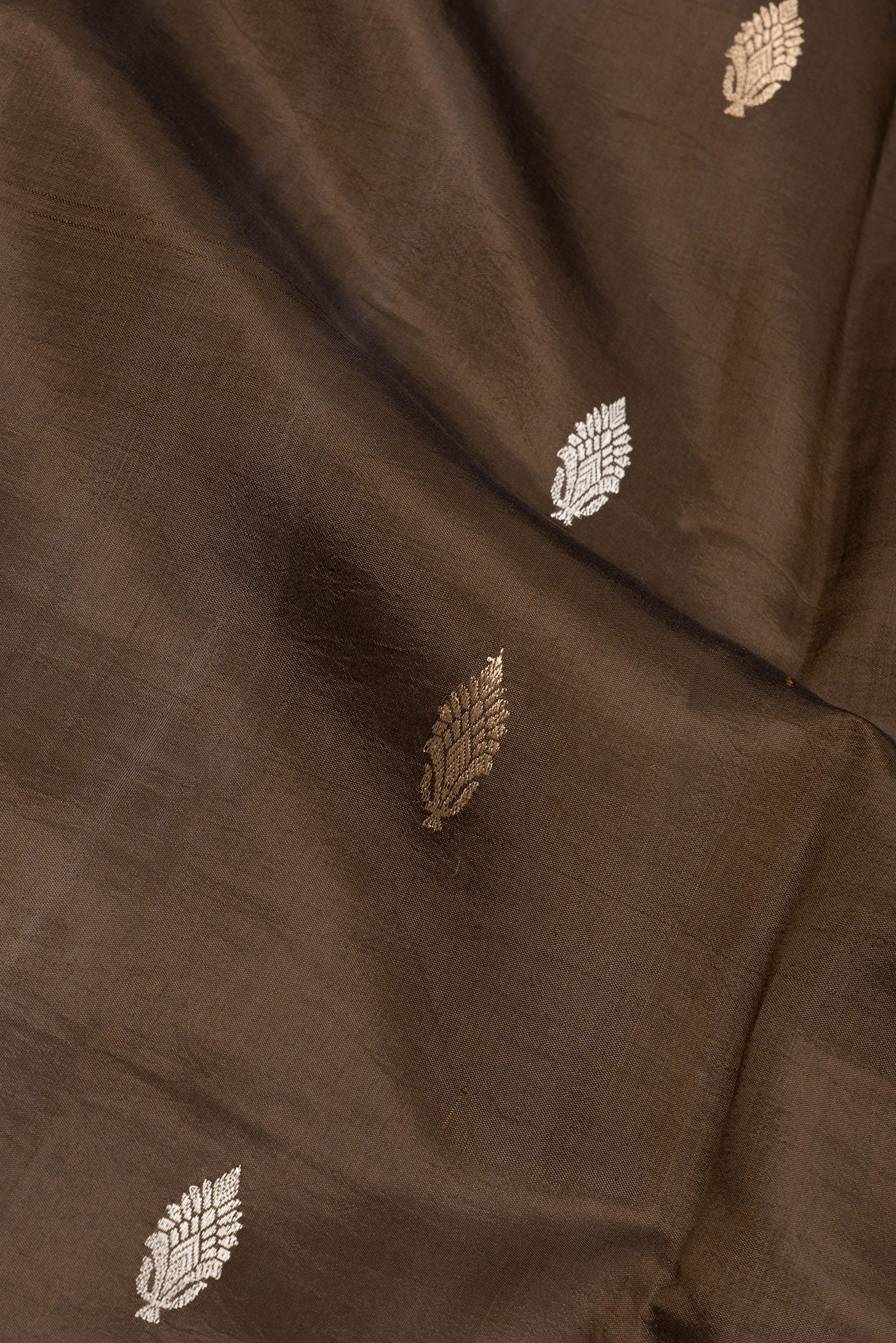 Close up of Brown Dual Tone Tussar Silk Saree with Zari Butta on the body and Fancy Border.  displaying folds