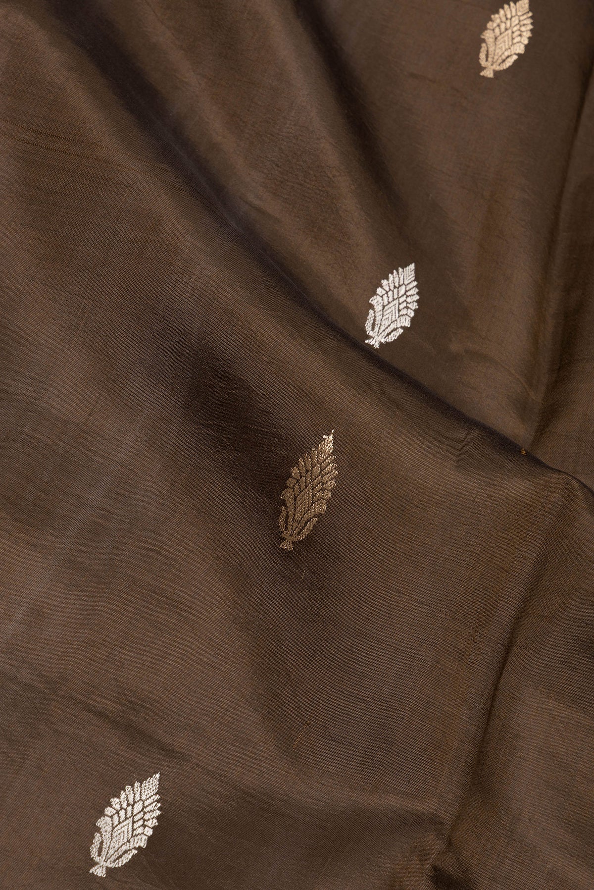 Close up of Brown Dual Tone Tussar Silk Saree with Zari Butta on the body and Fancy Border.  displaying folds
