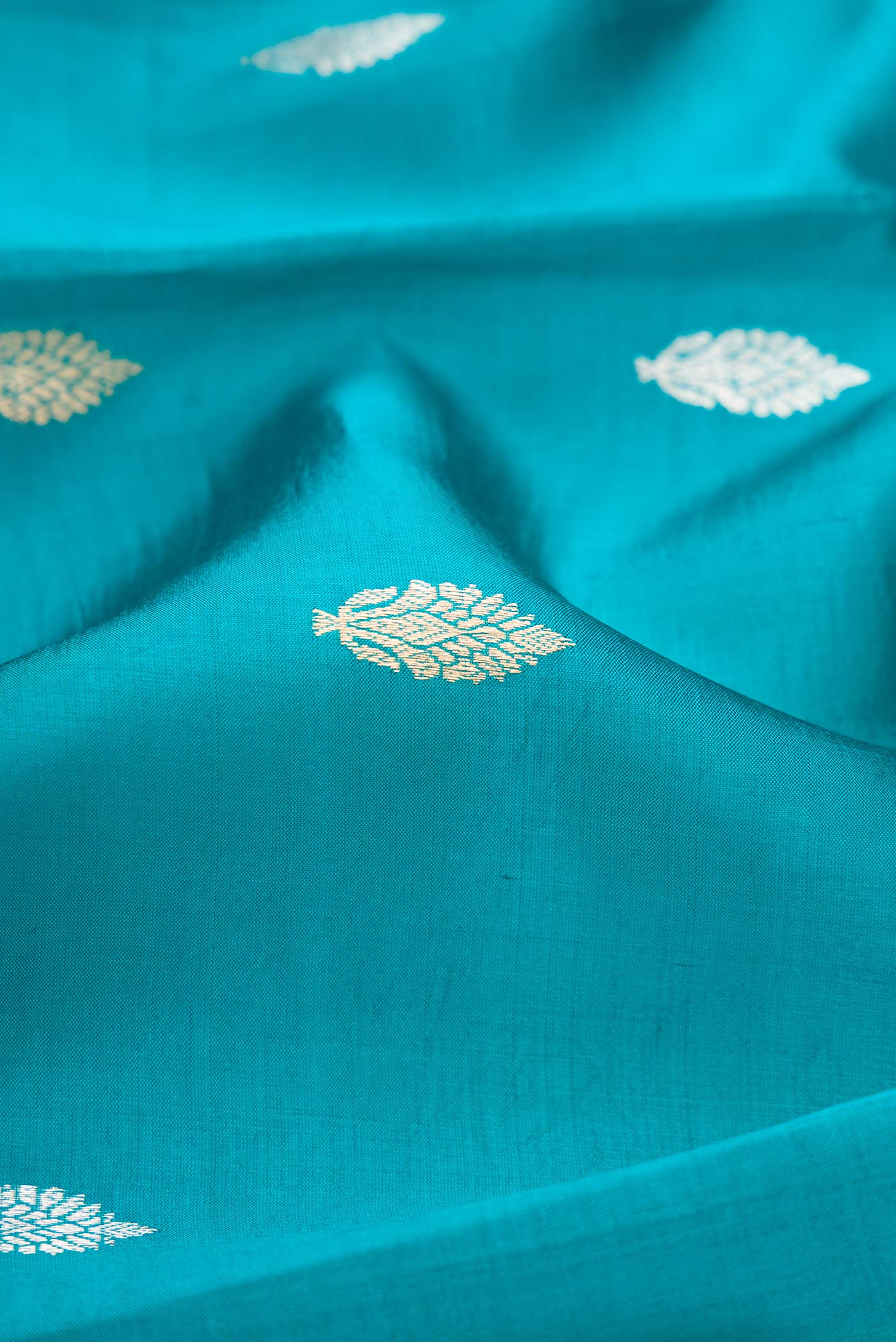Close up of Peacock Blue Dual Tone Tussar Silk Saree with Zari Butta on the body and Fancy Border.  displaying folds