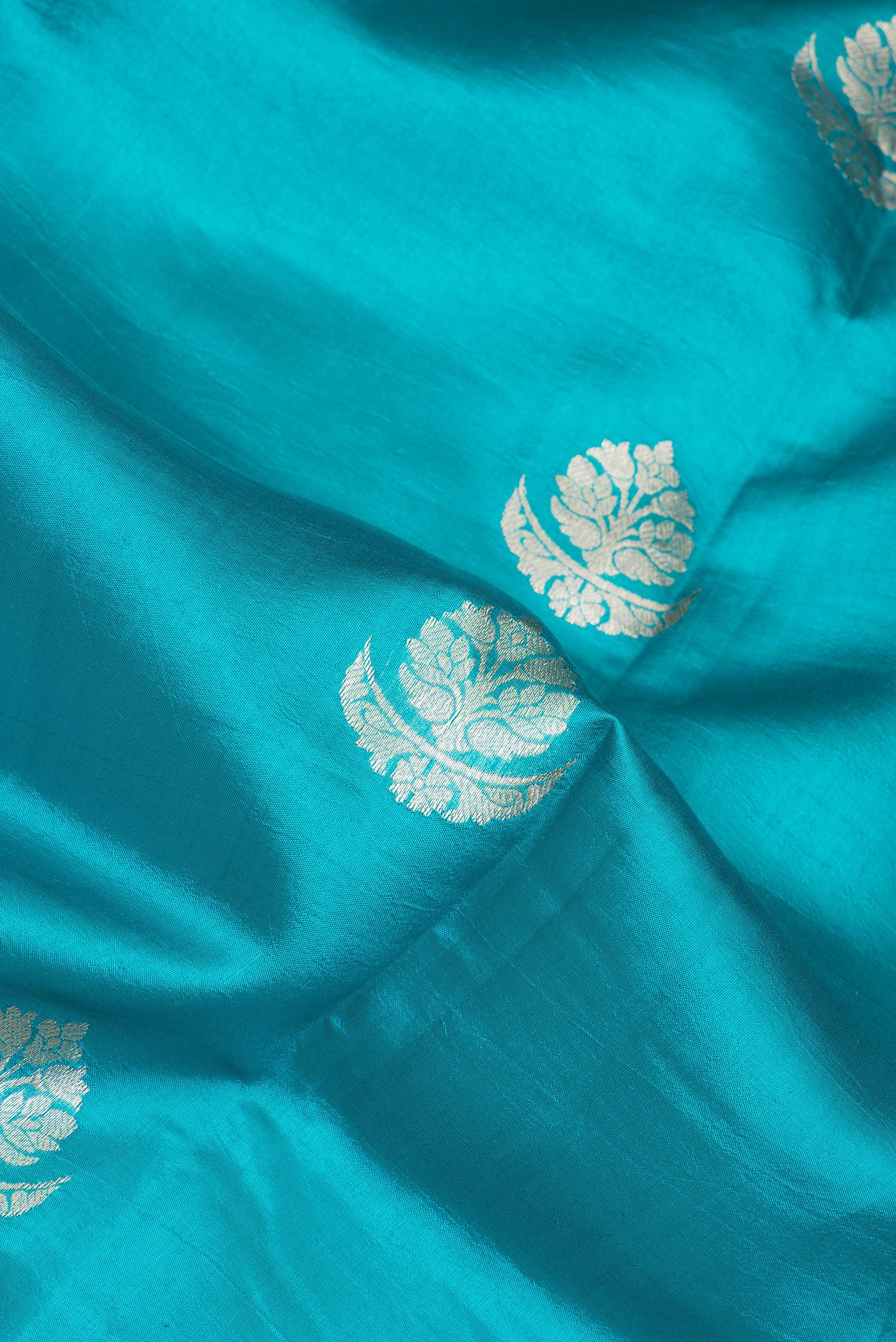 Close up of Sky Blue Tussar Silk Saree with Zari Butta on the body and Zari Border.  displaying folds