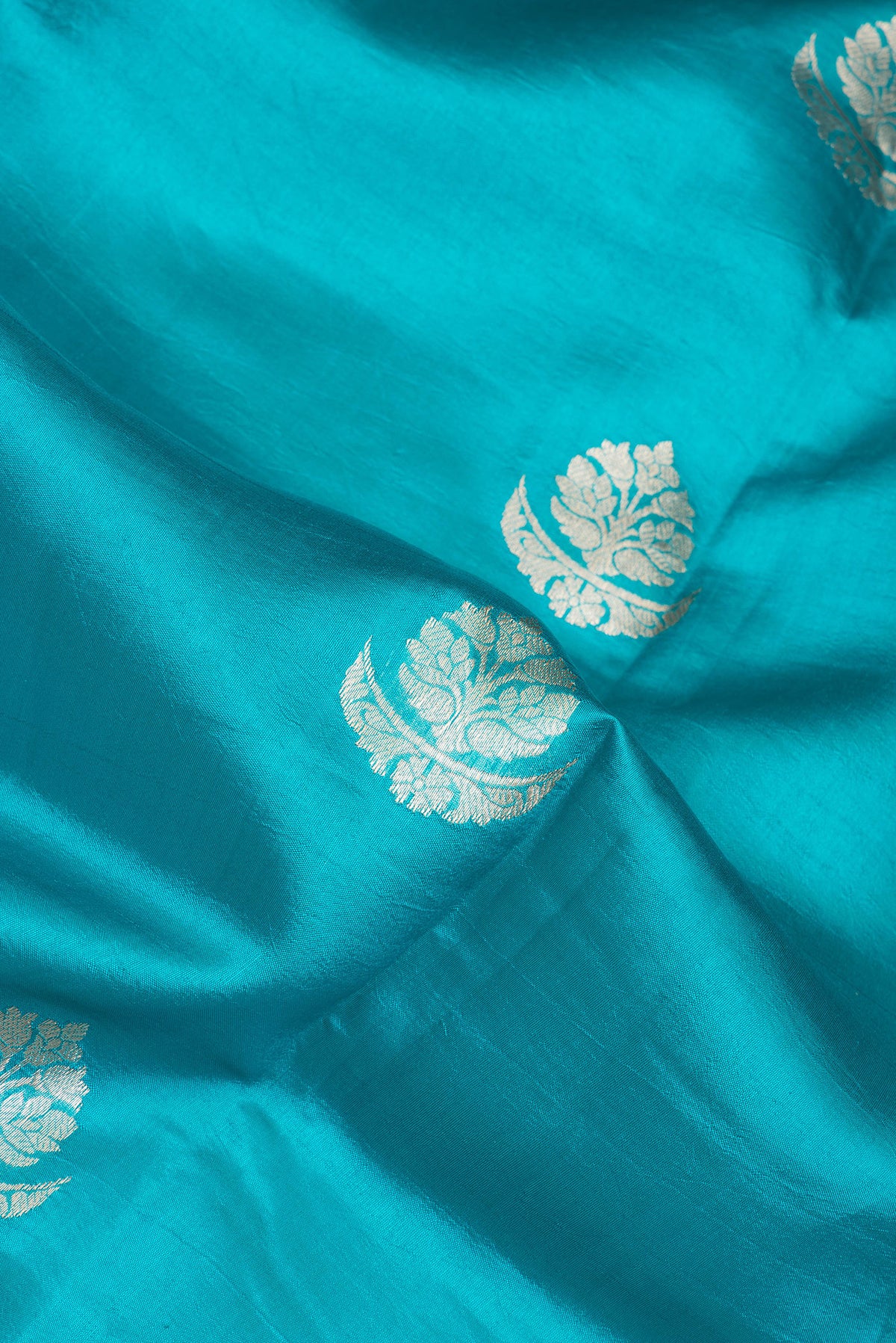 Close up of Sky Blue Tussar Silk Saree with Zari Butta on the body and Zari Border.  displaying folds
