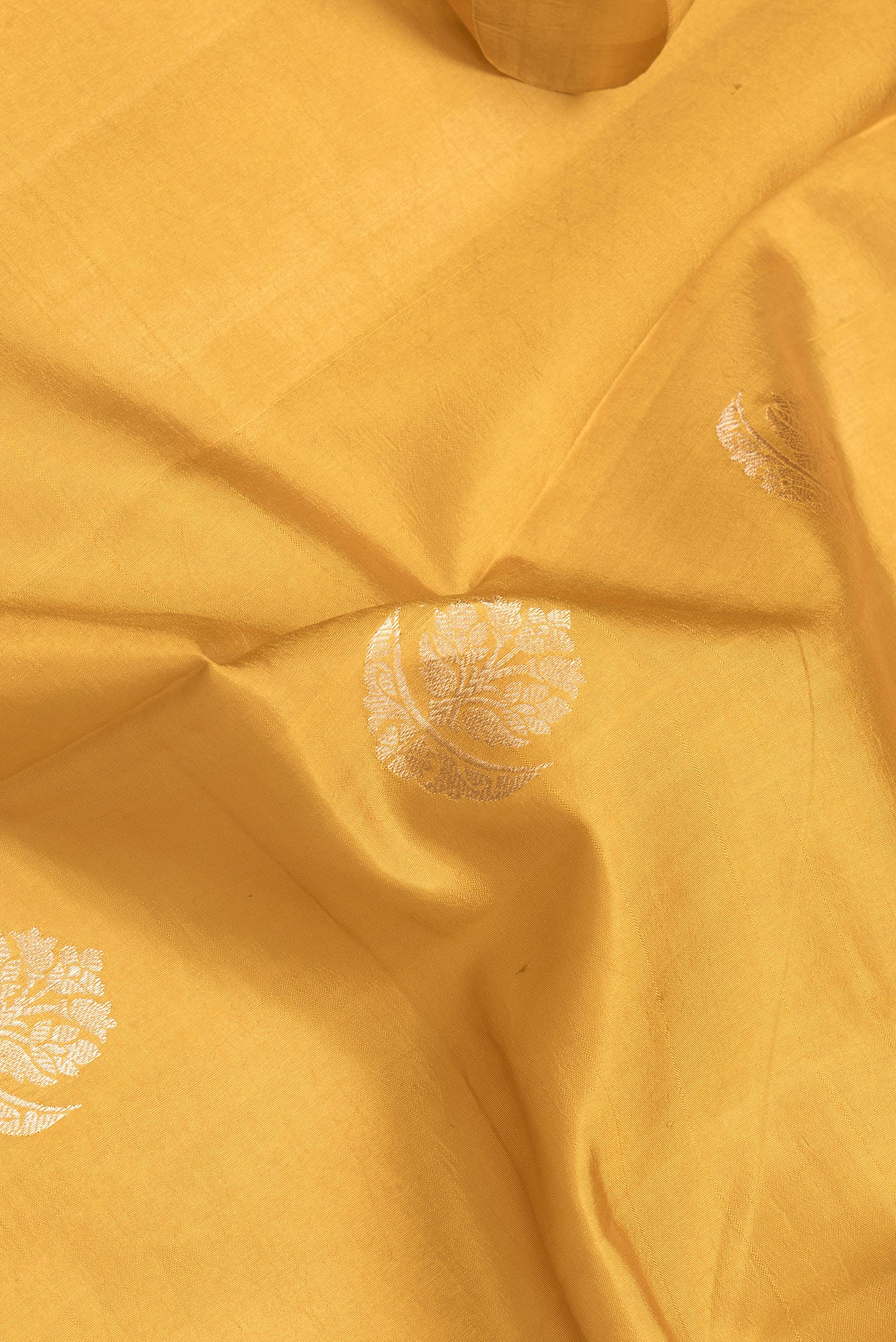 Close up of Mustard Dual Tone Tussar Silk Saree with Zari Butta on the body and Fancy Border.  displaying folds