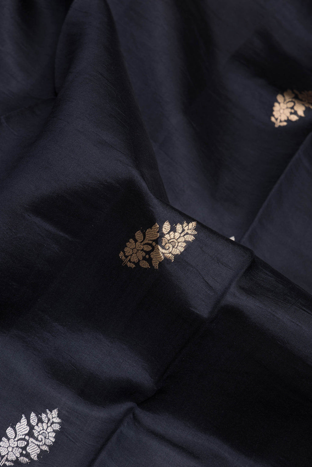 Close up of Black Dual Tone Tussar Silk Saree with Zari Butta on the body and Fancy Border.  displaying folds