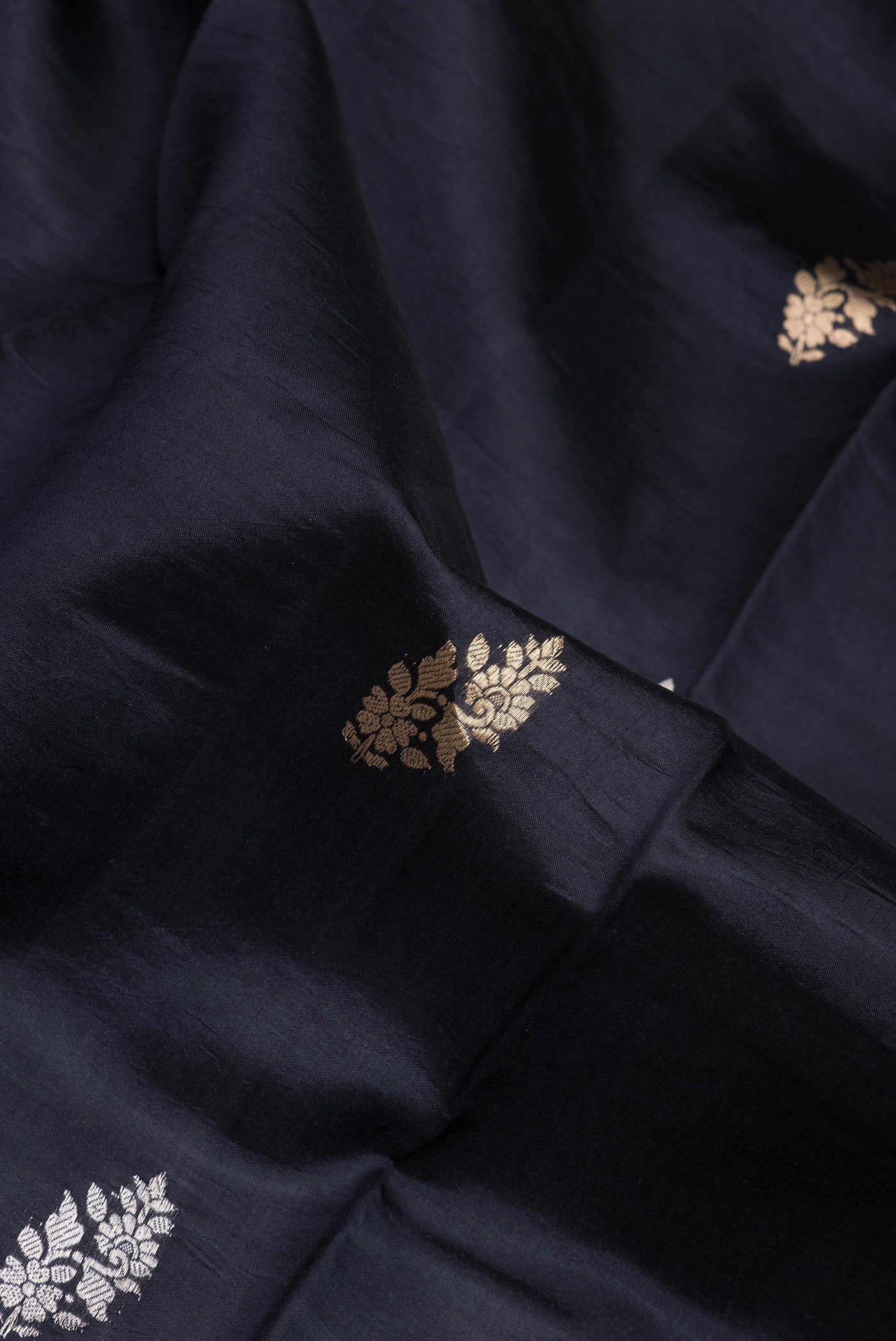 Close up of Black Dual Tone Tussar Silk Saree with Zari Butta on the body and Fancy Border.  displaying folds