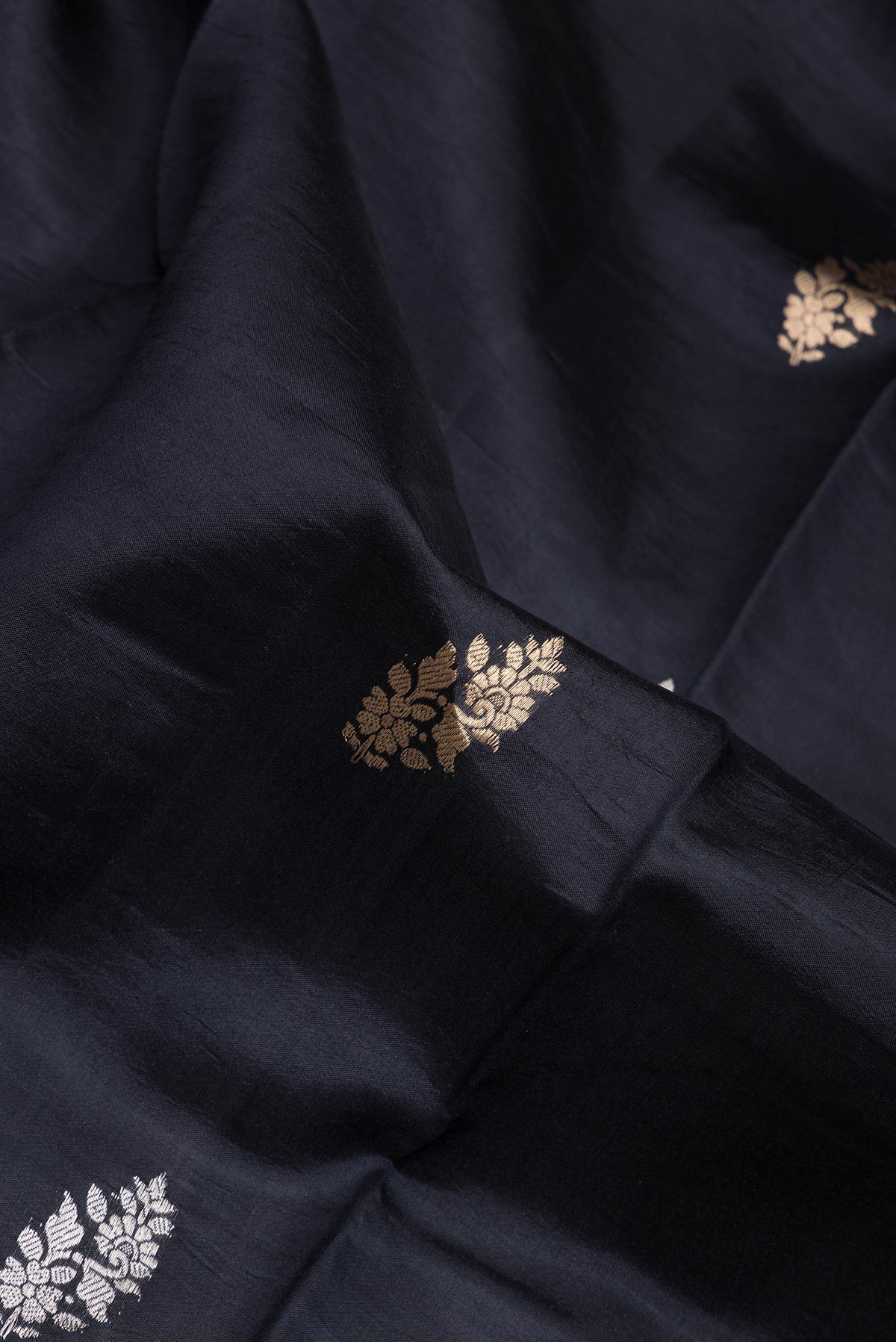 Close up of Black Dual Tone Tussar Silk Saree with Zari Butta on the body and Fancy Border.  displaying folds