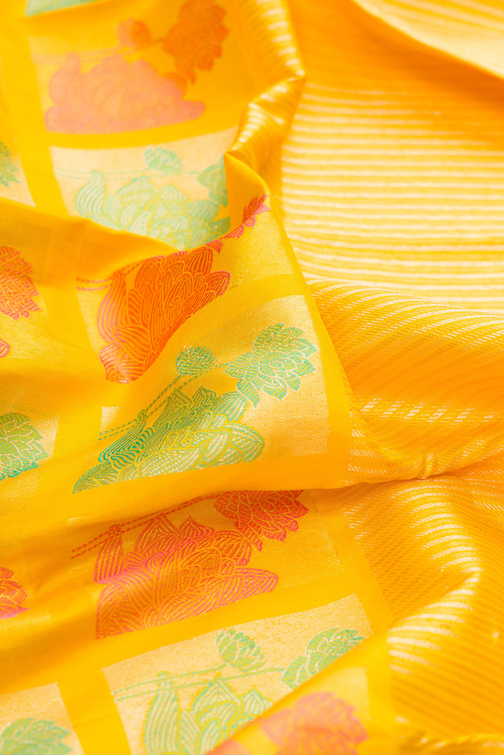 Close up of Yellow Kanjivaram Silk Saree with Stripes on the body and Fancy Border.  displaying folds