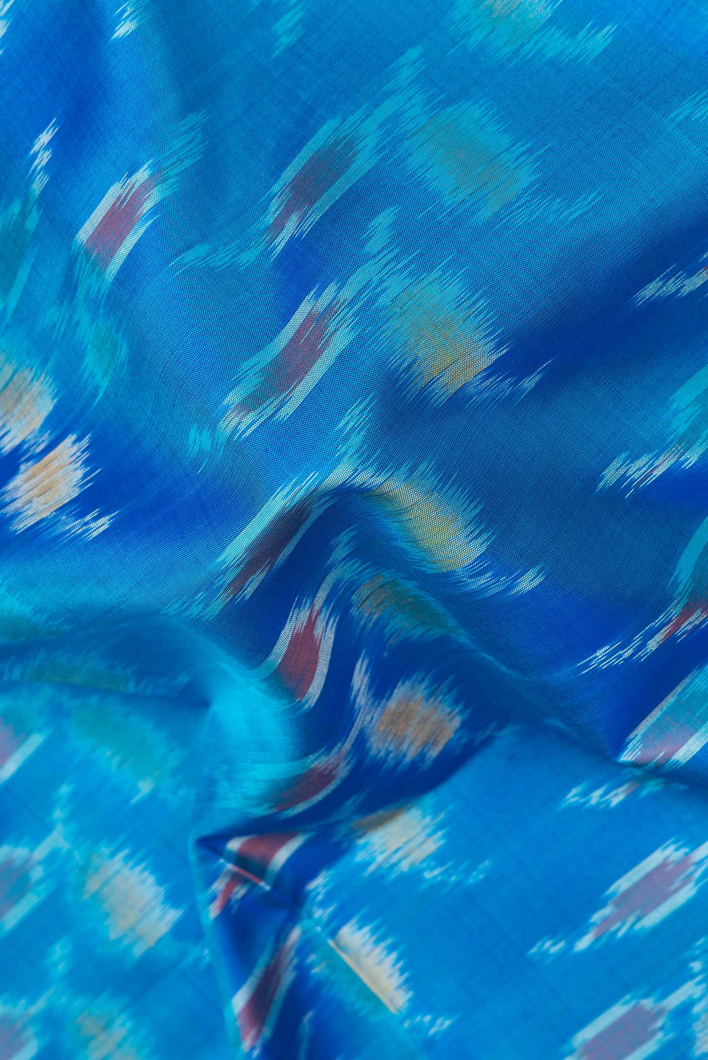Close up of Pure Silk Peacock Blue Dual Tone Soft Saree with Ikat Print on the body and Zari Border.  displaying folds