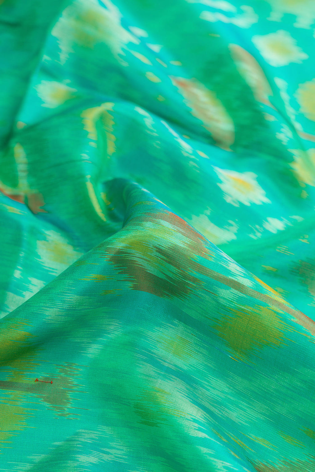 Close up of Sea Green Dual Tone Soft Silk Saree with Ikat Print on the body and Zari Border.  displaying folds