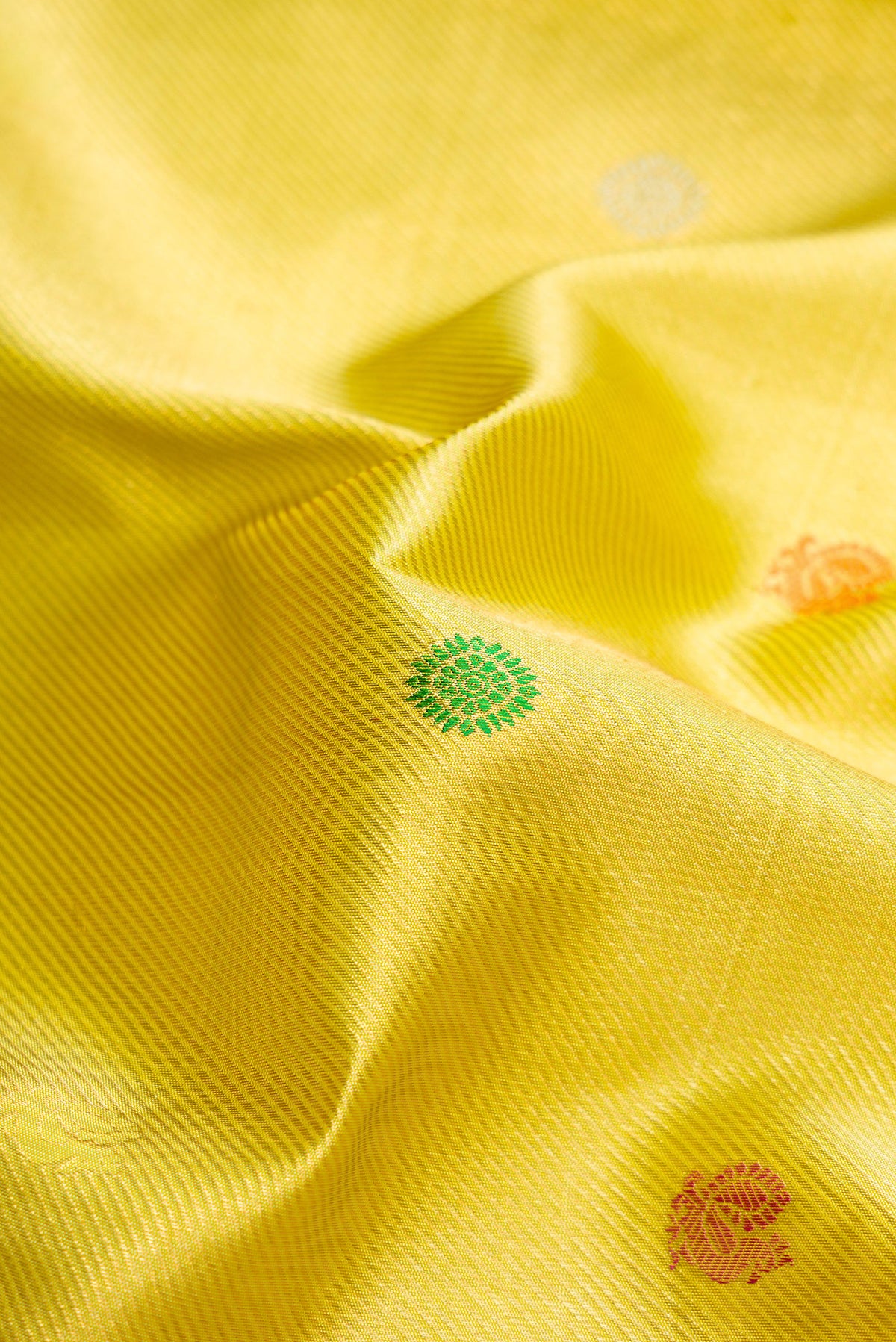 Close up of Lemon Yellow Dual Tone Kanchipuram Silk Saree with Zari Brocade on the body and Zari Border.  displaying folds