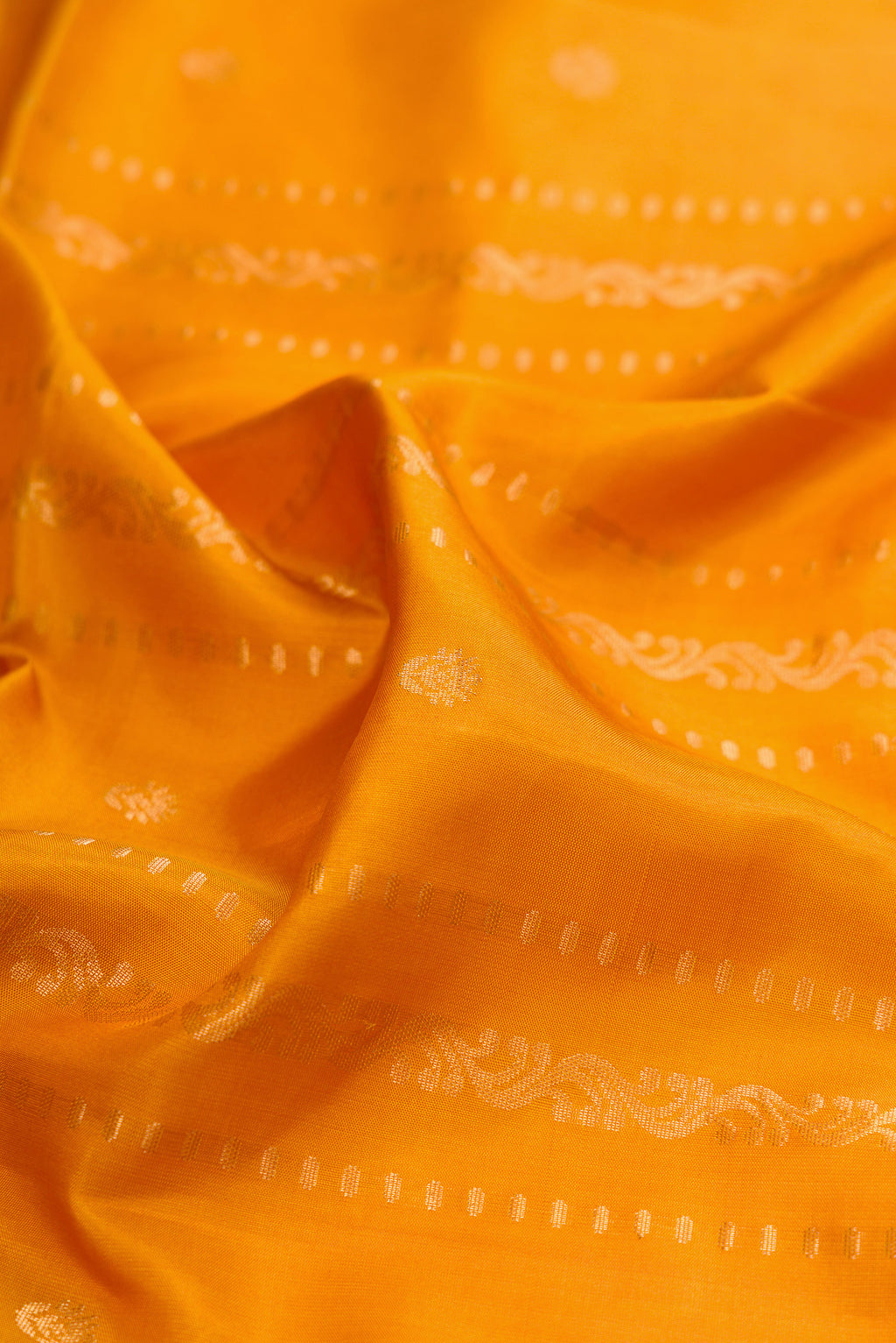 Close up of Mustard Soft Silk Saree with Zari Butta on the body and Zari Border.  displaying folds