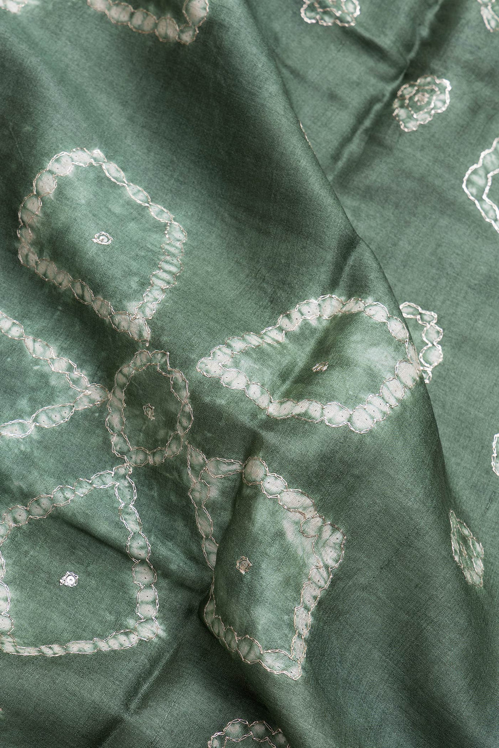 Close up of Mehandi Green Dual Tone Tussar Silk Saree with Embroidery on the body and Without Border.  displaying folds