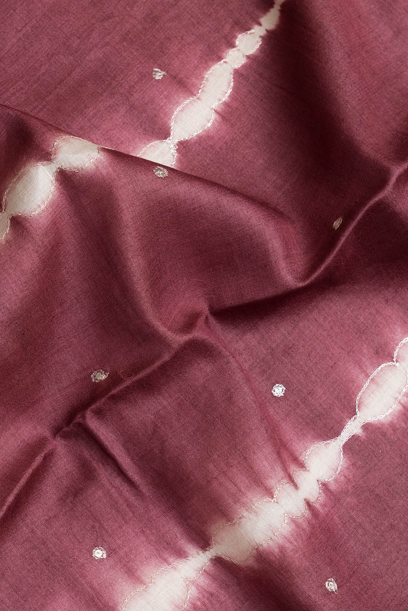 Close up of Maroon Dual Tone Tussar Silk Saree with Embroidery on the body and Without Border.  displaying folds