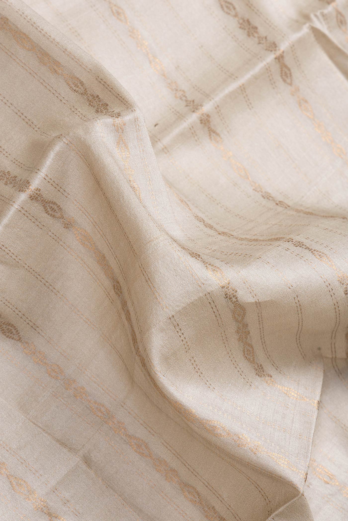 Close up of Beige Dual Tone Tussar Silk Saree with Stripes on the body and Printed Border.  displaying folds