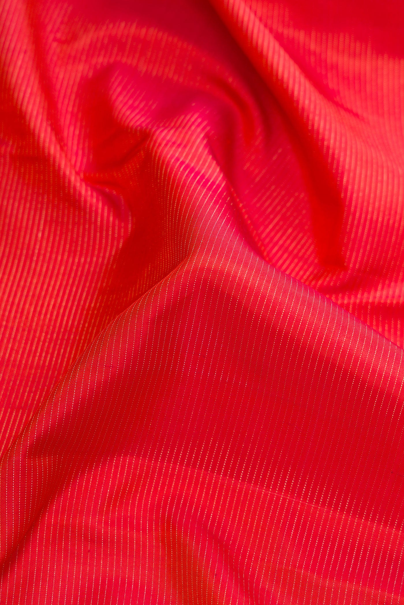 Close up of Brick Orange Dual Tone Kanjivaram Silk Saree with Stripes on the body and Checks Border.  displaying folds