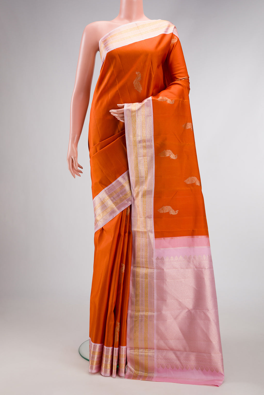 Pure Silk Pure Zari Brick Orange Dual Tone Kanjivaram Saree with Zari Butta on the body and Zari Border.  displayed on a mannequin