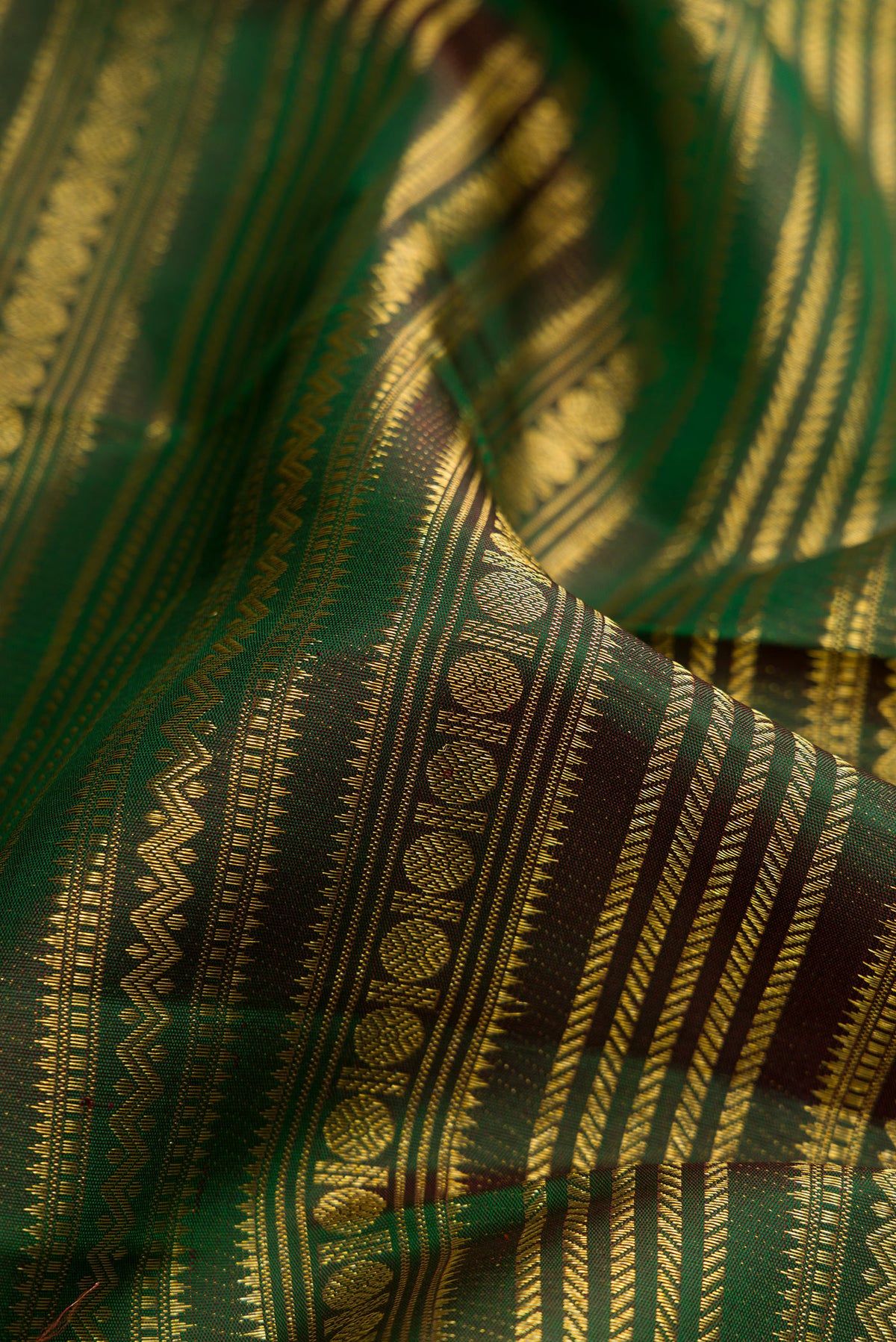 Close up of Bottle Green Kanchipuram Silk Saree with Zari Brocade on the body and Zari Border.  displaying folds