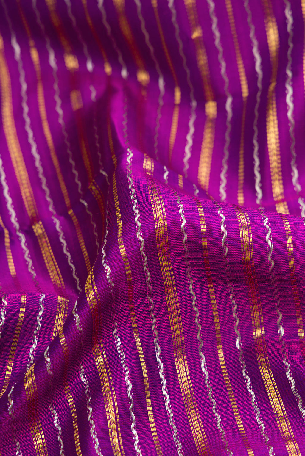 Close up of Magenta Dual Tone Kanchipuram Silk Saree with Stripes on the body and Zari Border.  displaying folds