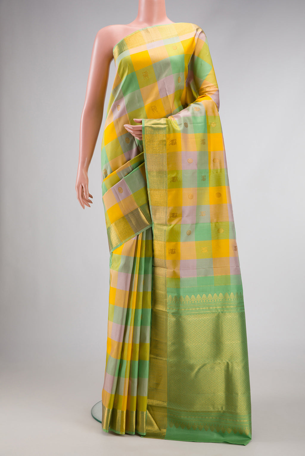 Yellow , Green and Lilac Color Kanchipuram Silk Saree with Checked design on the body and Zari Border.  displayed on a mannequin