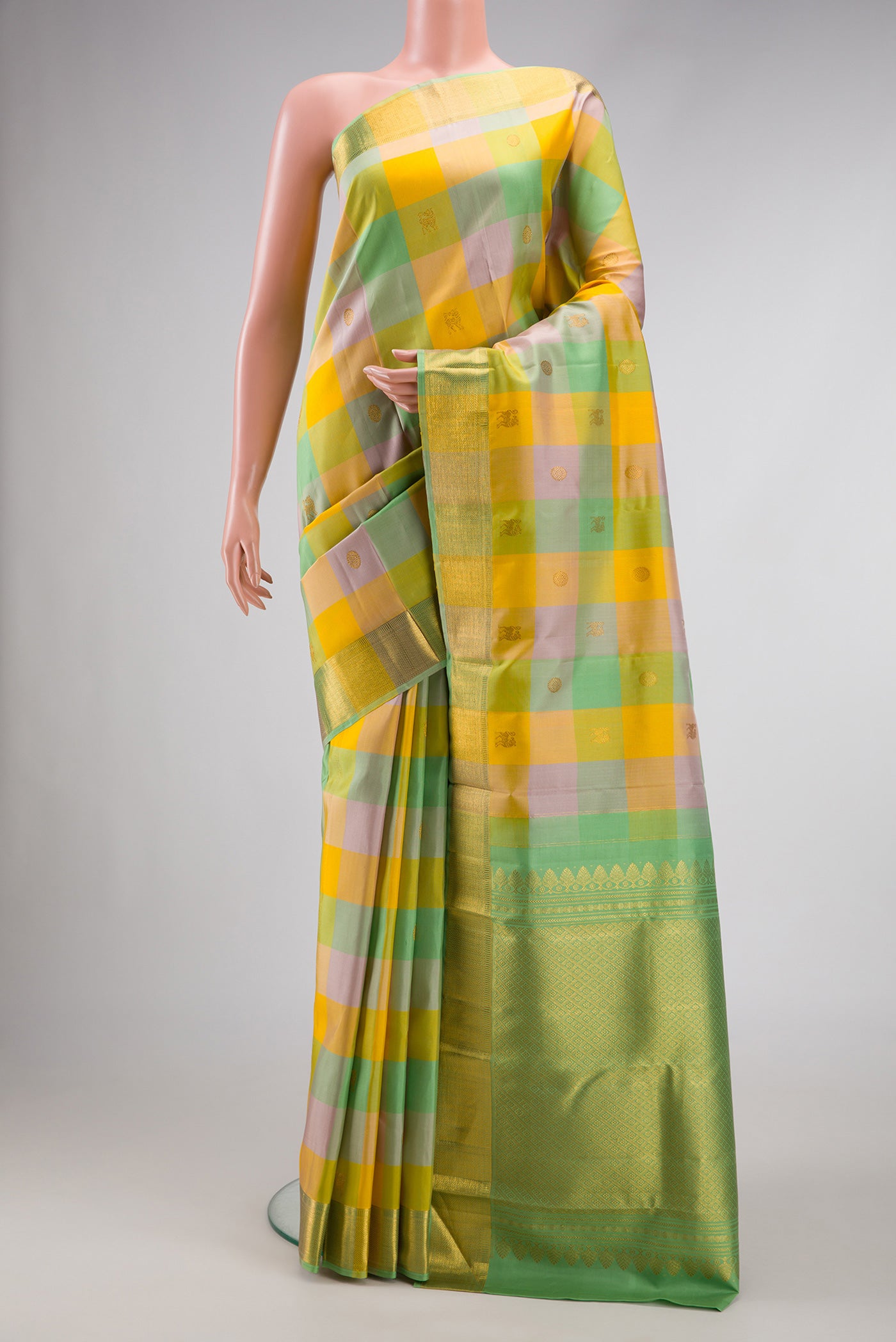 Yellow , Green and Lilac Color Kanchipuram Silk Saree with Checked design on the body and Zari Border.  displayed on a mannequin