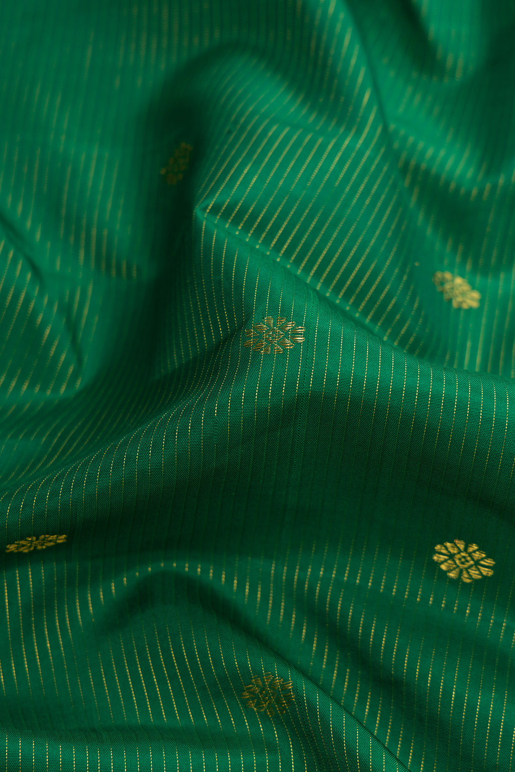 Close up of Pure Silk Pure Zari Green Dual Tone Kanjivaram Saree with Zari Butta on the body and Zari Border.  displaying folds