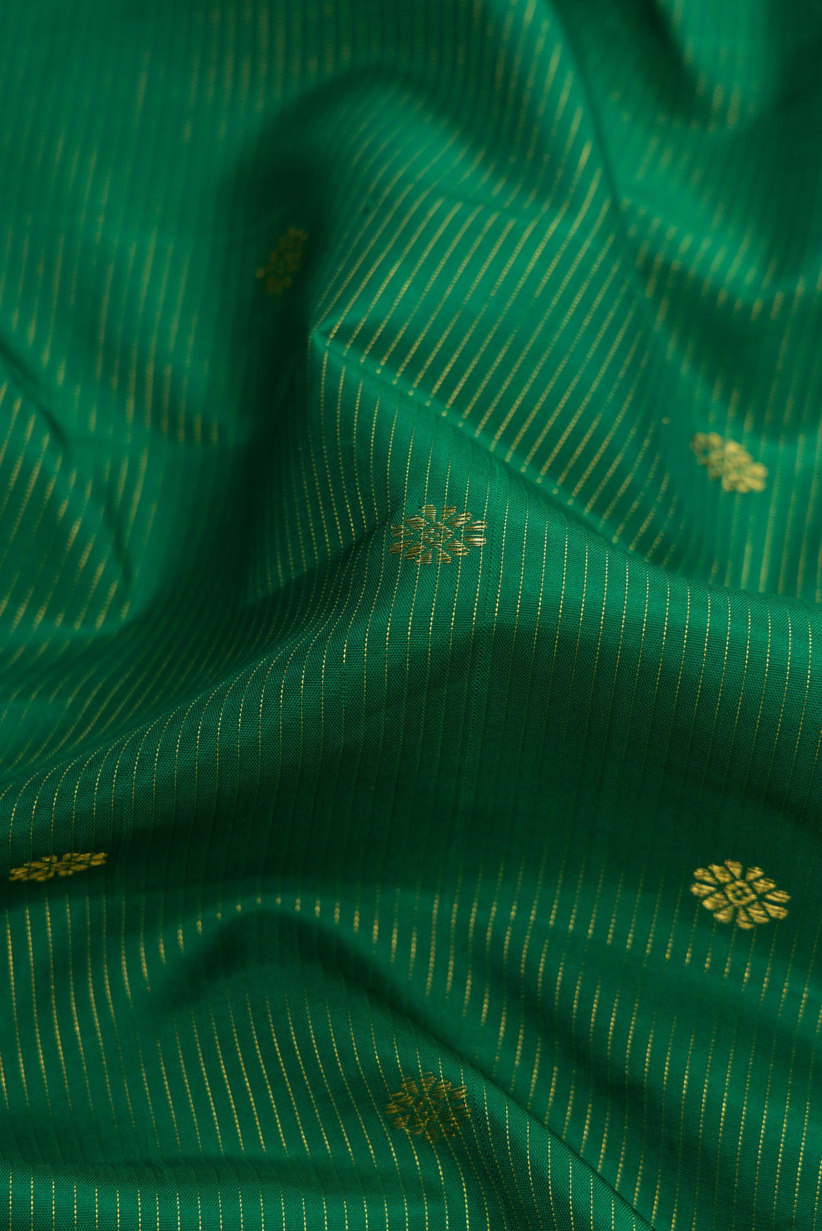 Close up of Pure Silk Pure Zari Green Dual Tone Kanjivaram Saree with Zari Butta on the body and Zari Border.  displaying folds