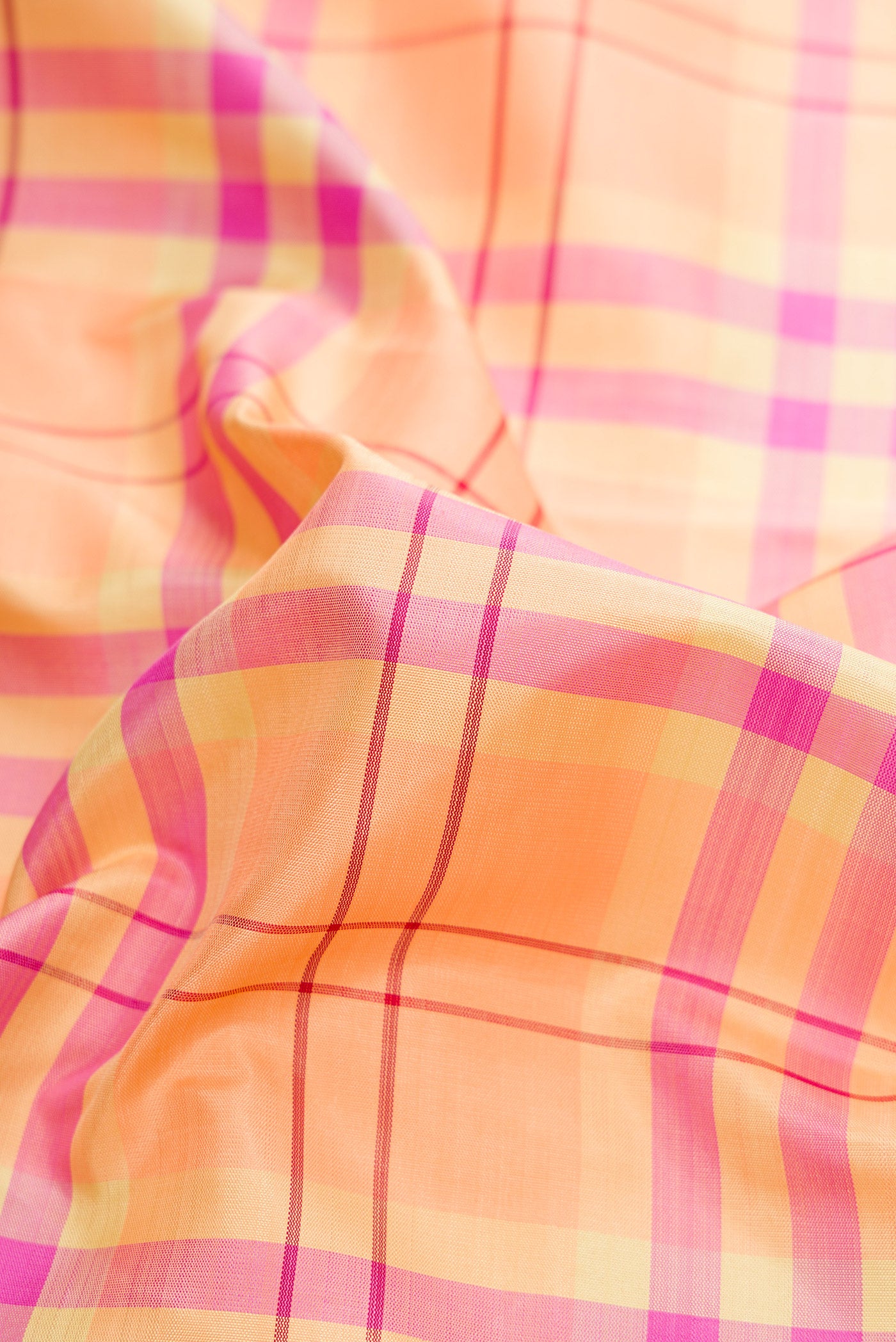 Close up of Pure Silk Pure Zari Peach Dual Tone Kanchipuram Saree with Checked design on the body and Zari Border.  displaying folds