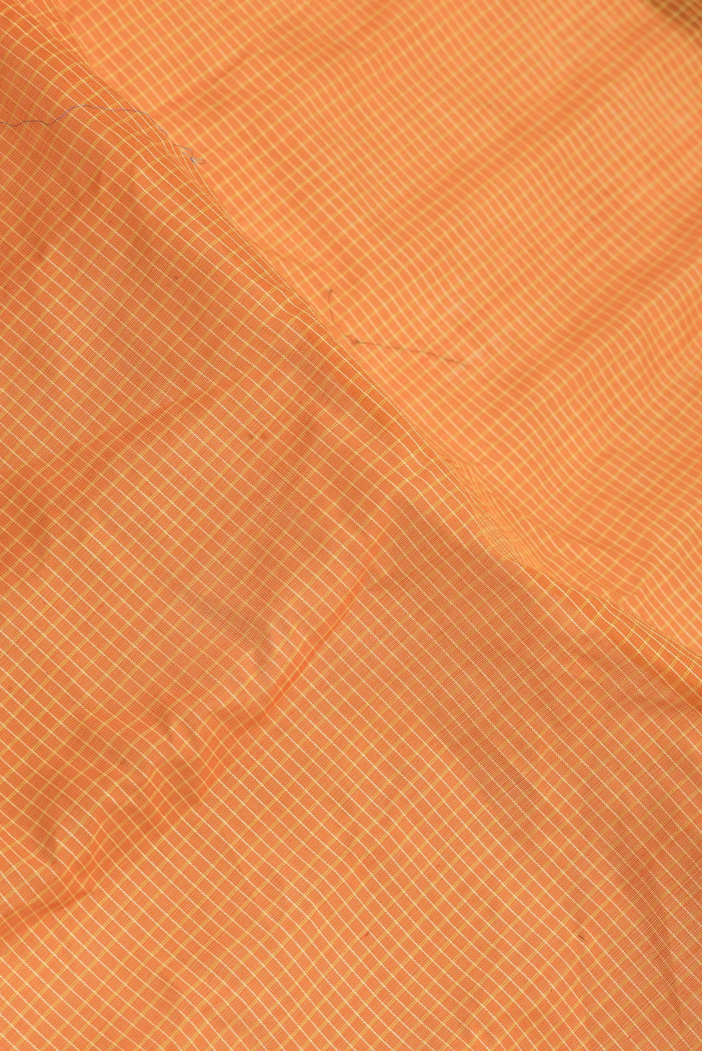 Close up of Orange Dual Tone Gadwal Silk Saree with Checked design on the body and Zari Border.  displaying folds