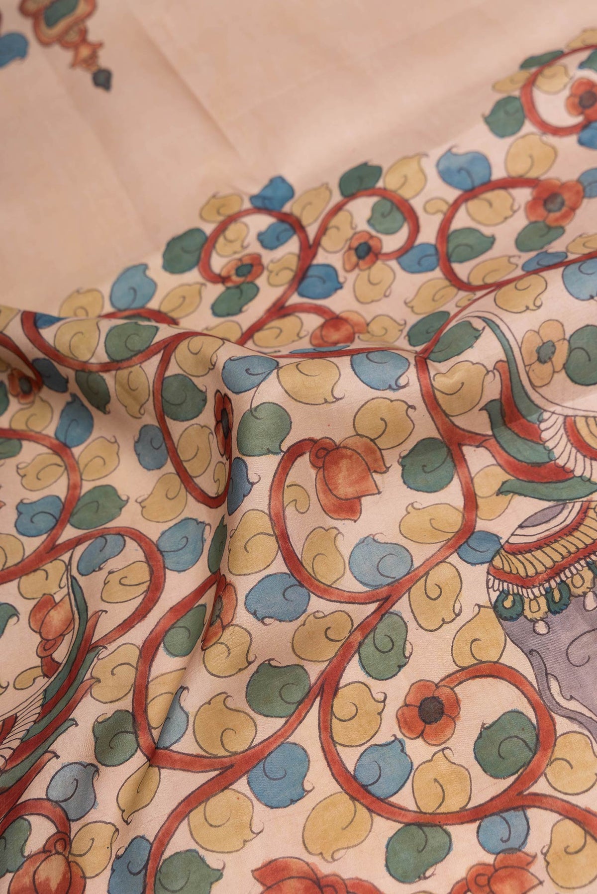 Close up of Beige Dual Tone Kanchipuram Silk Saree with kalamkari Print on the body and Zari Border.  displaying folds