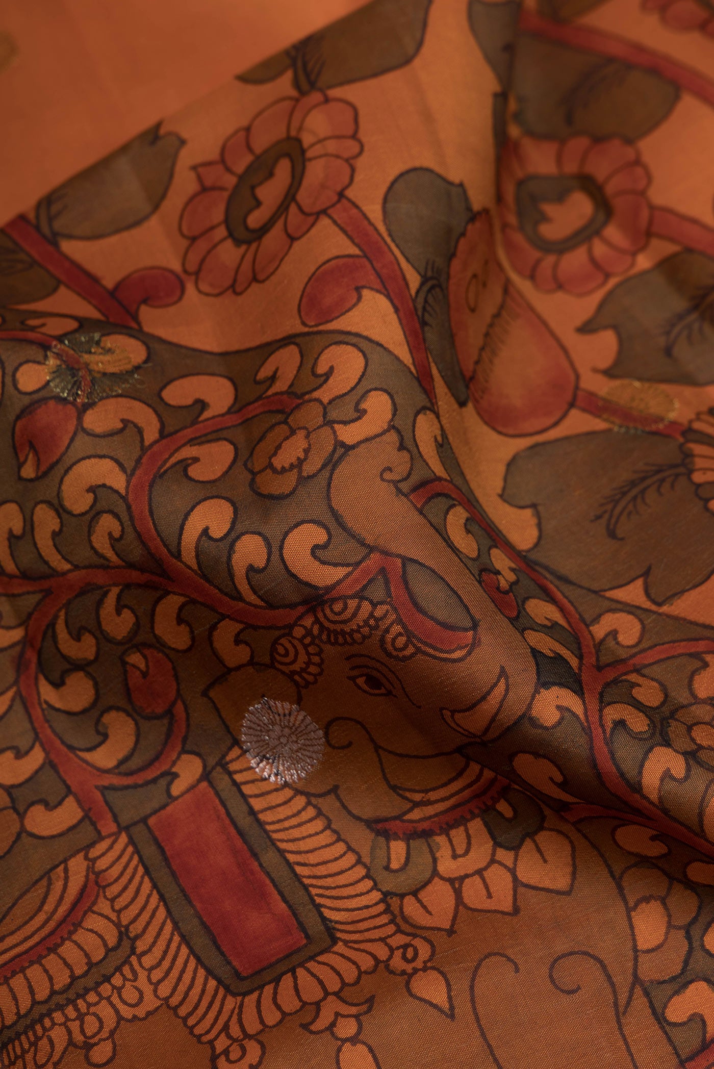 Close up of Orange Dual Tone Kanchipuram Silk Saree with kalamkari Print on the body and Zari Border.  displaying folds