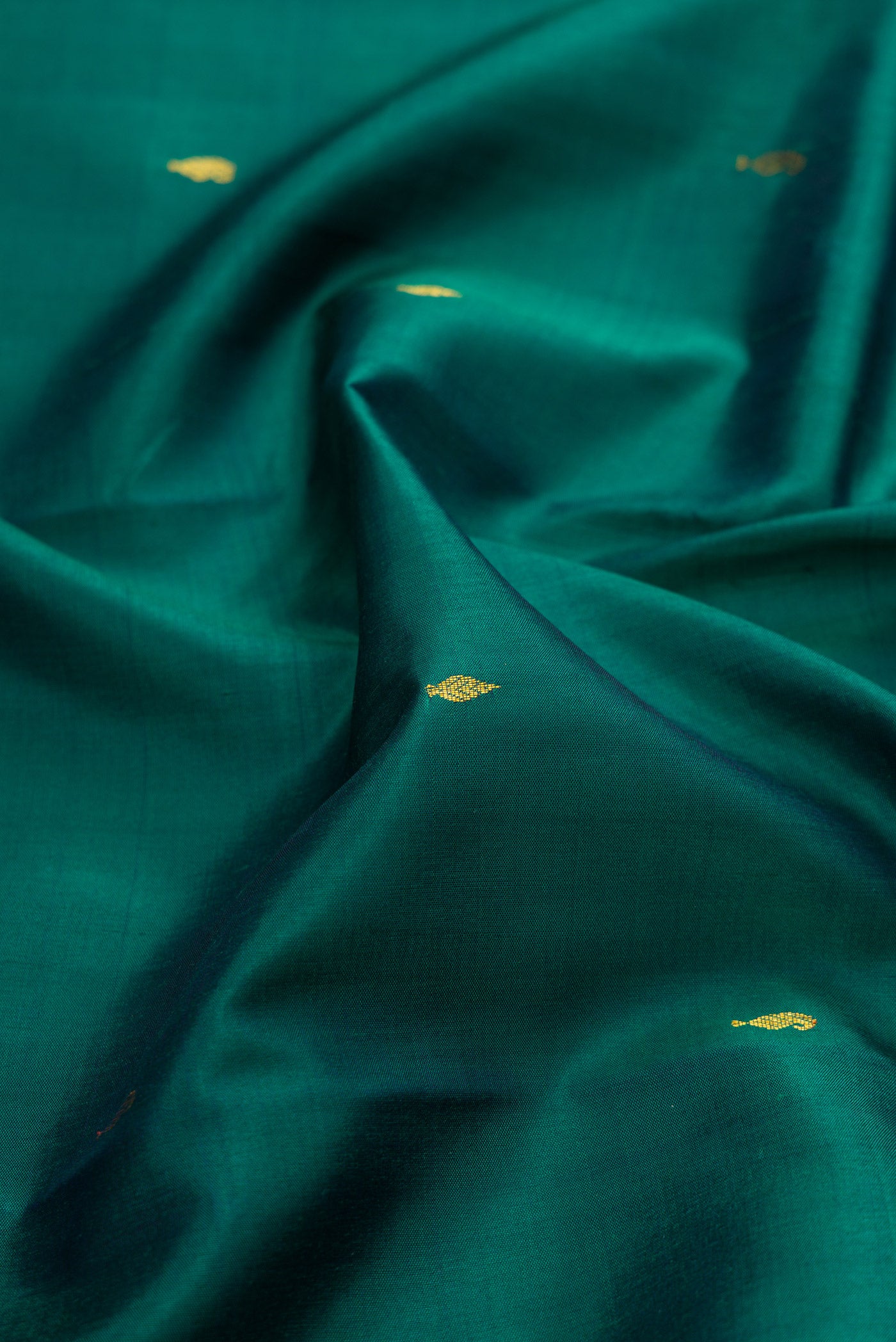 Close up of Bottle Green Kanchipuram Silk Saree with Zari Butta on the body and Zari Border.  displaying folds