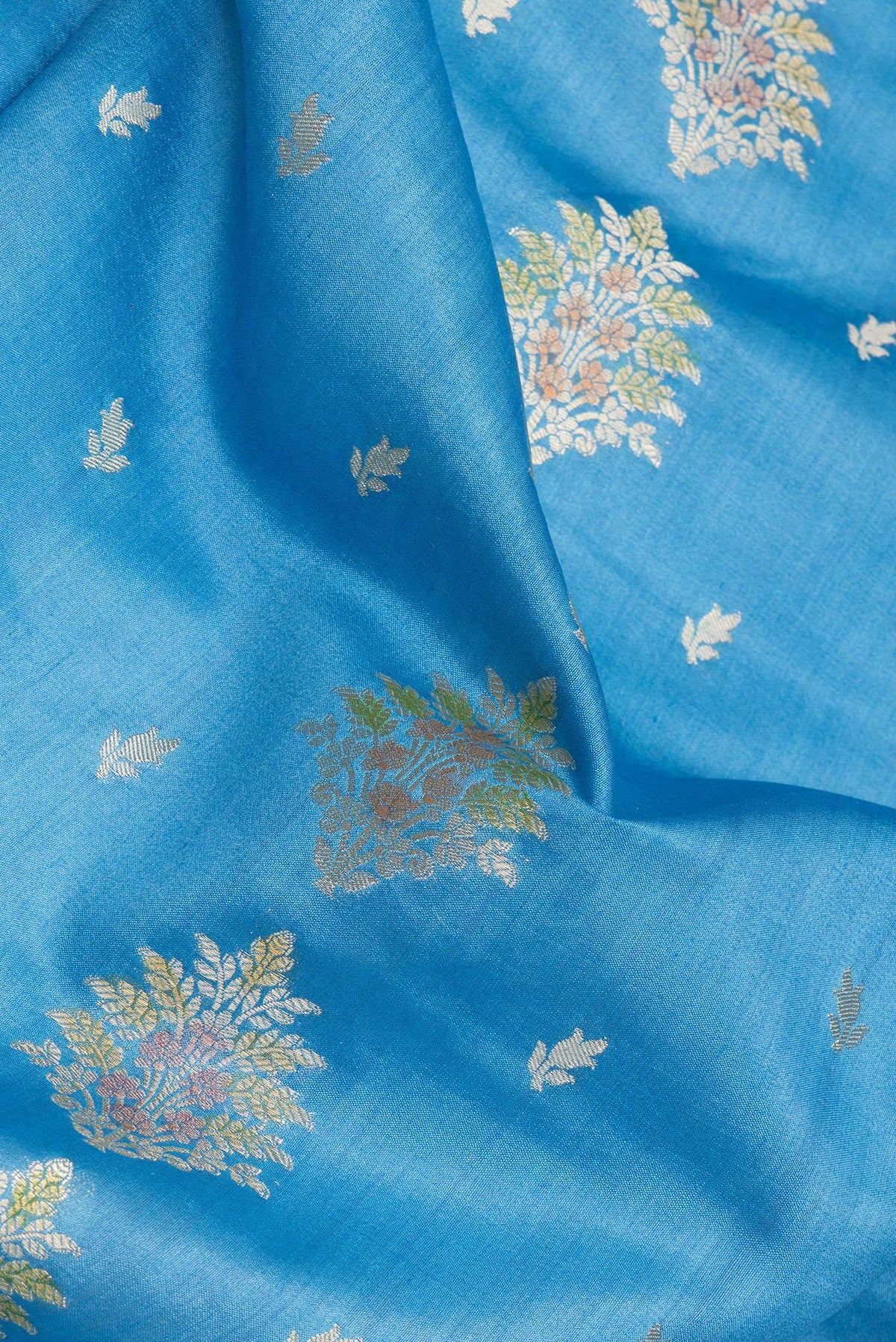 Close up of Sky Blue Dual Tone Tussar Silk Saree with Zari Butta on the body and Zari Border.  displaying folds