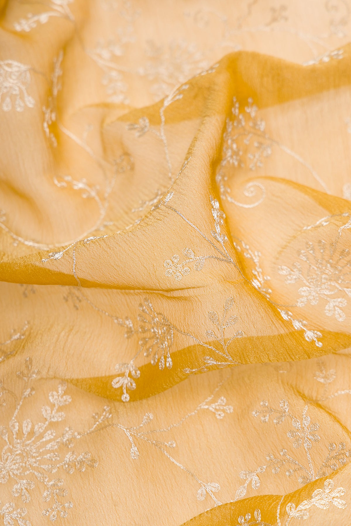 Close up of Mustard Dual Tone Organza Silk Saree with Embroidery on the body and Embroidery Border.  displaying folds