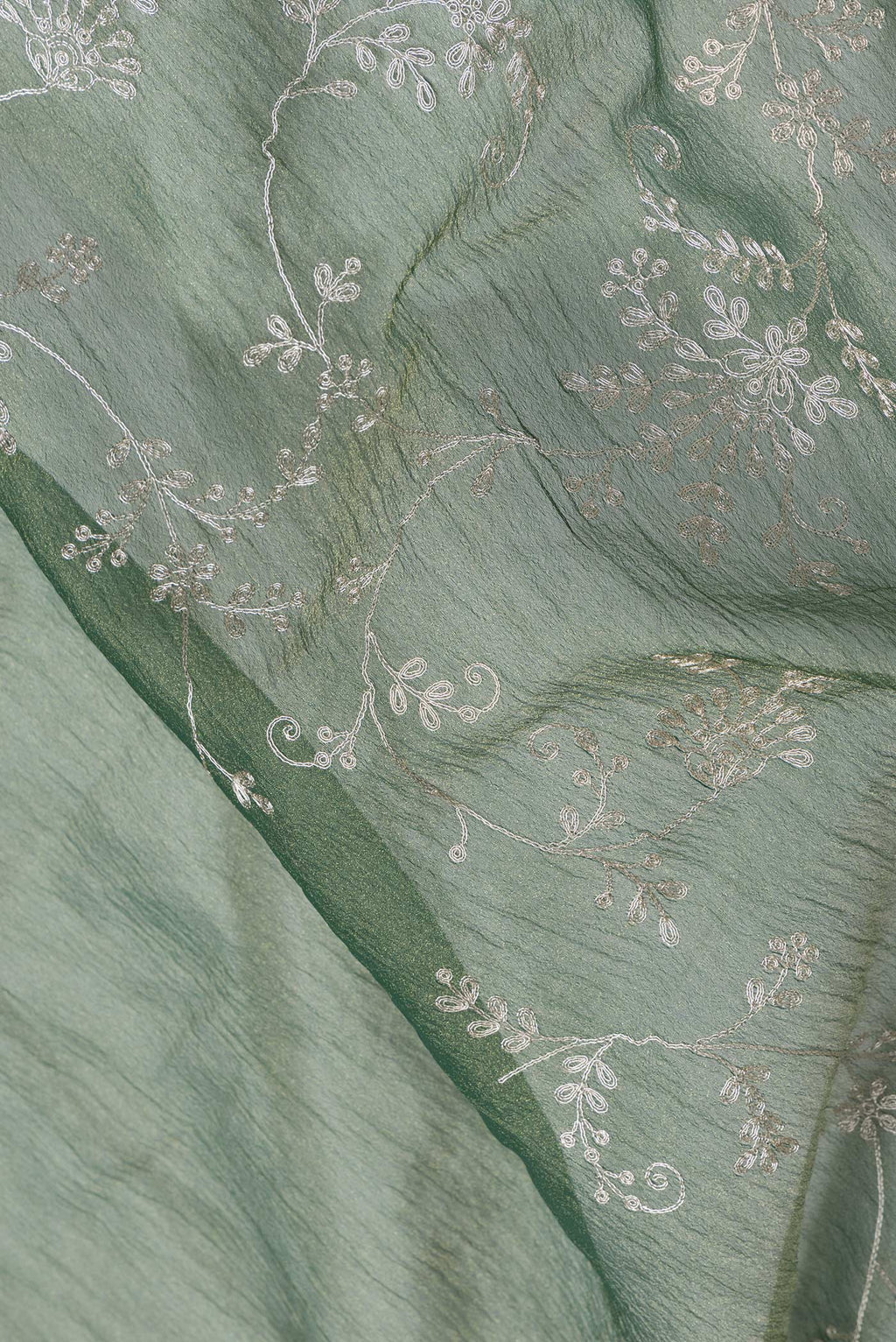 Close up of Green Dual Tone Organza Silk Saree with Embroidery on the body and Embroidery Border.  displaying folds