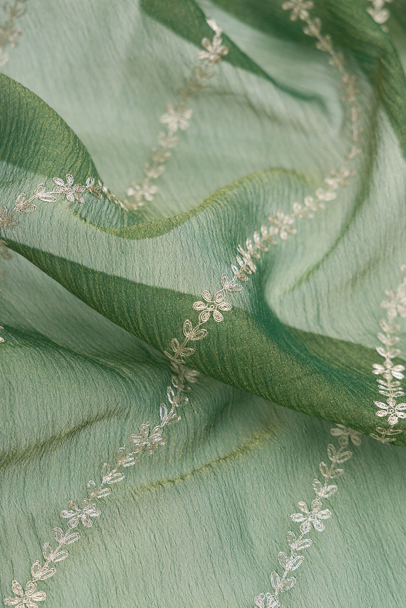 Close up of Green Dual Tone Organza Silk Saree with Embroidery on the body and Embroidery Border.  displaying folds
