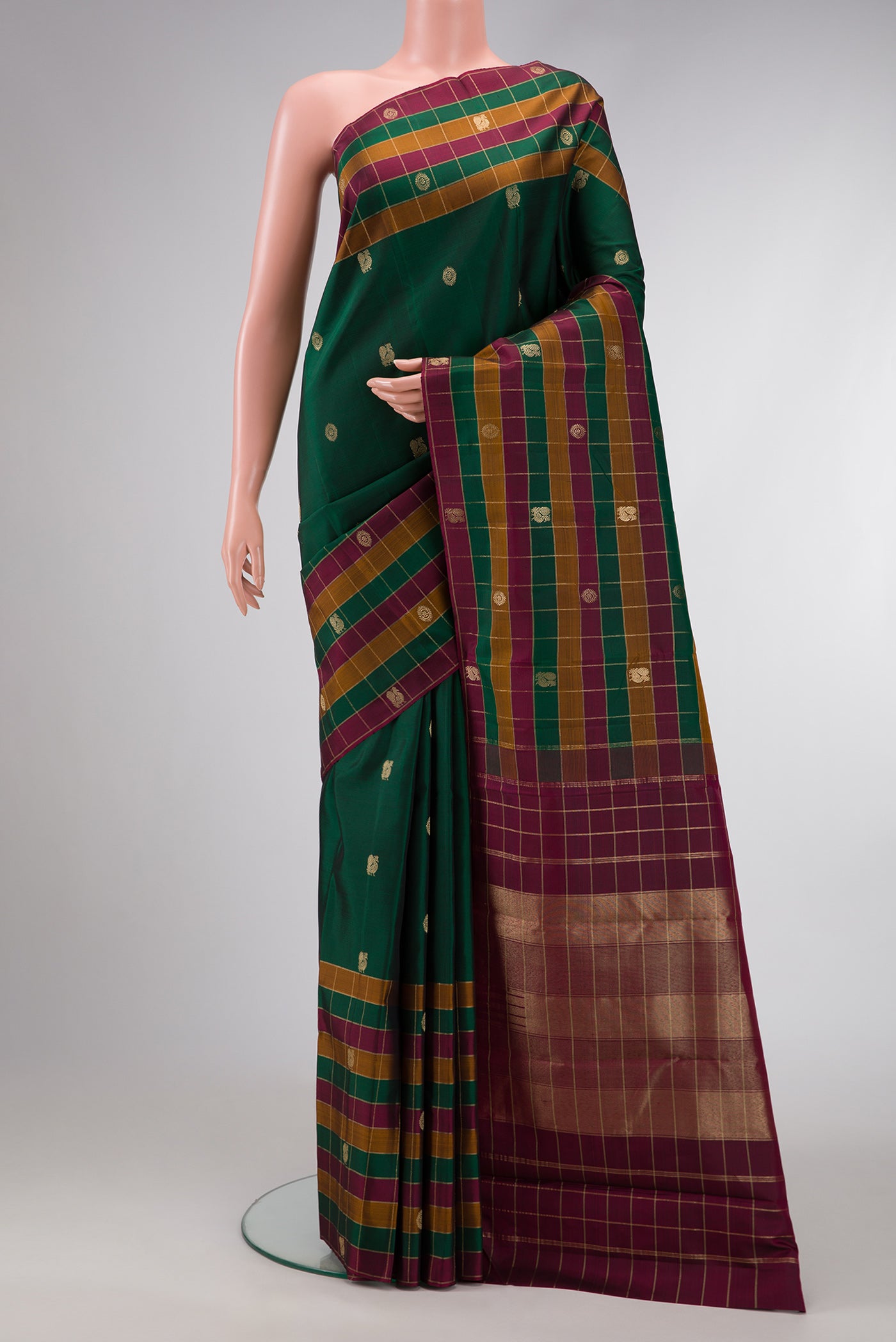 Bottle Green Dual Tone Kanjivaram Silk Saree with Zari Butta on the body and Checks Border.  displayed on a mannequin
