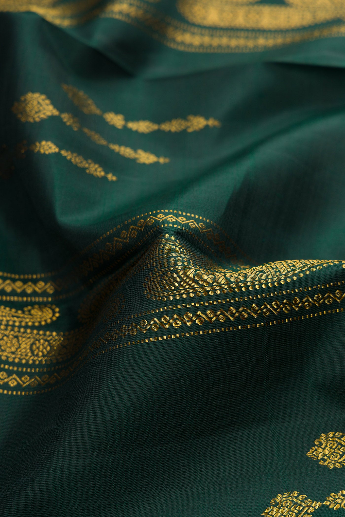 Close up of Bottle Green Kanchipuram Silk Saree with Zari Butta on the body and Without Border.  displaying folds